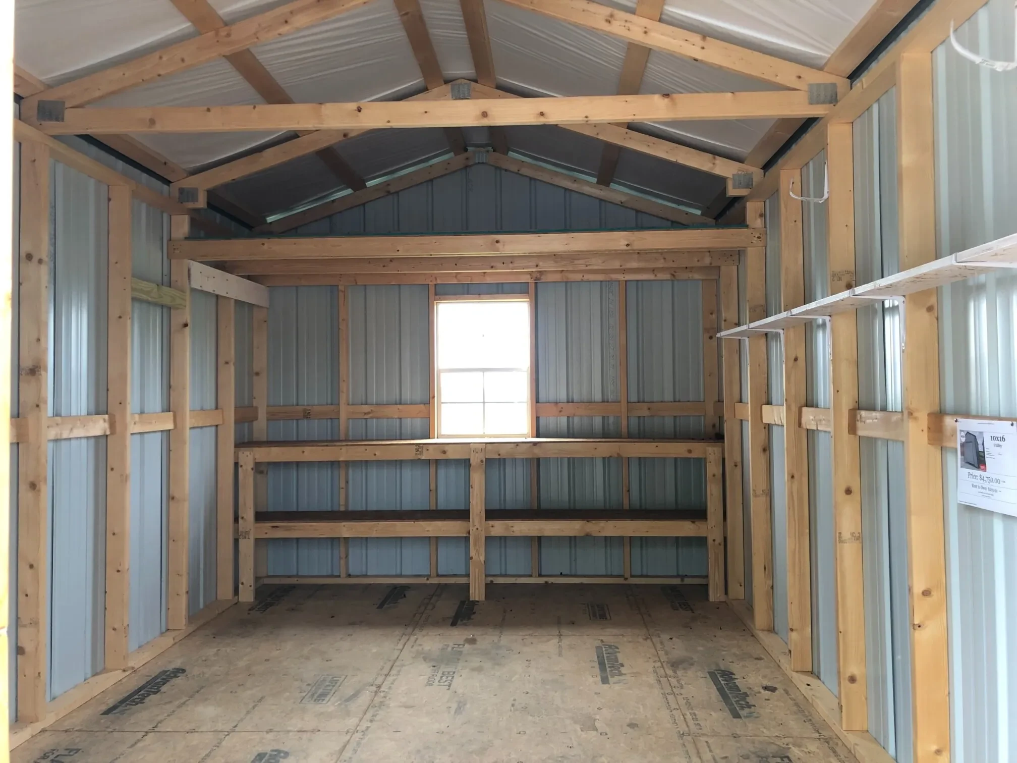 The inside of a metal shed showing double shelves, a loft, and a window along the back wall