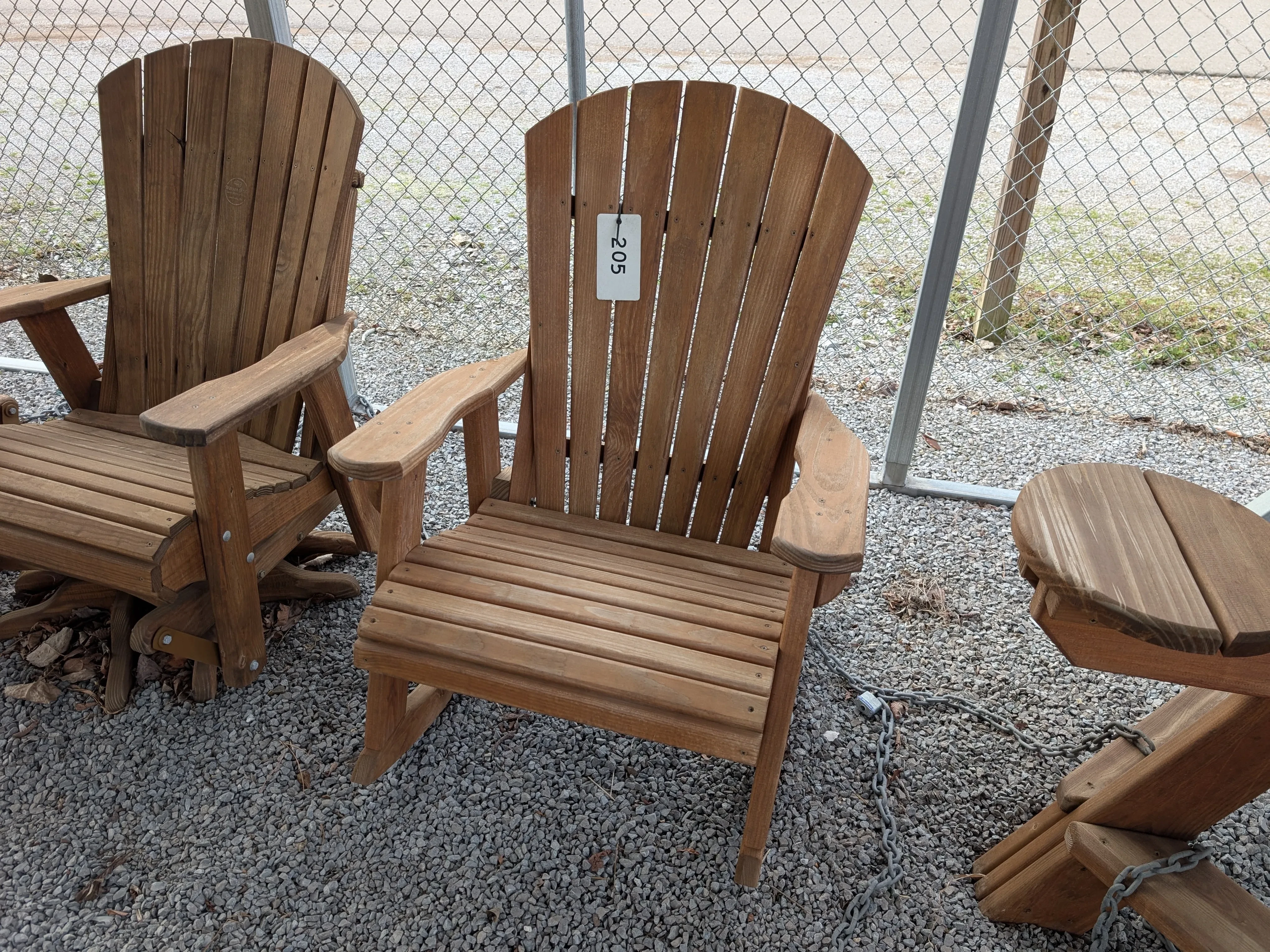 a rocking chair sitting in the gravel. It is stained and sealed. It has a price tag on it