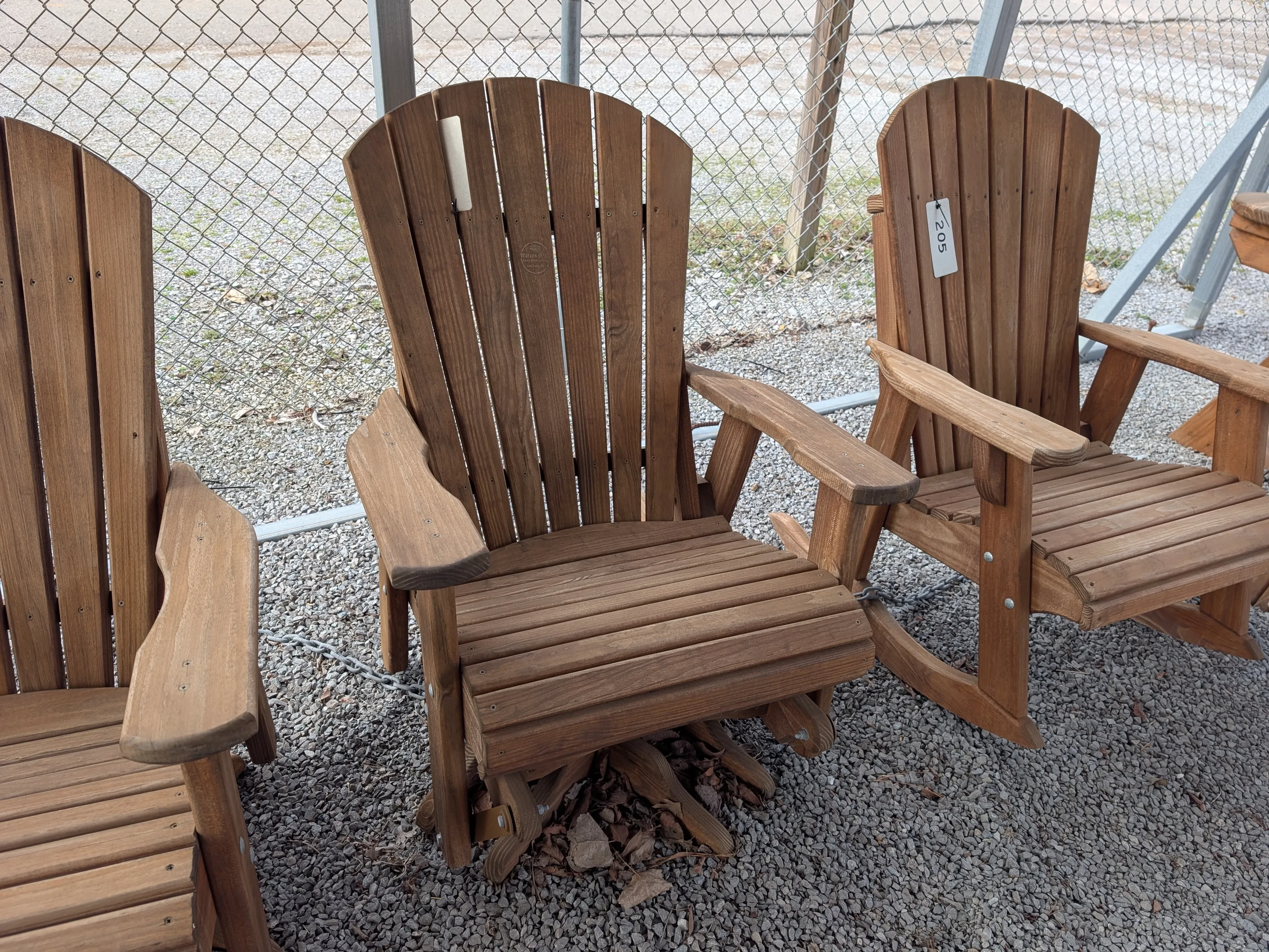 a wood chair that swivels around and glides back and forth. It is sitting in gravel.