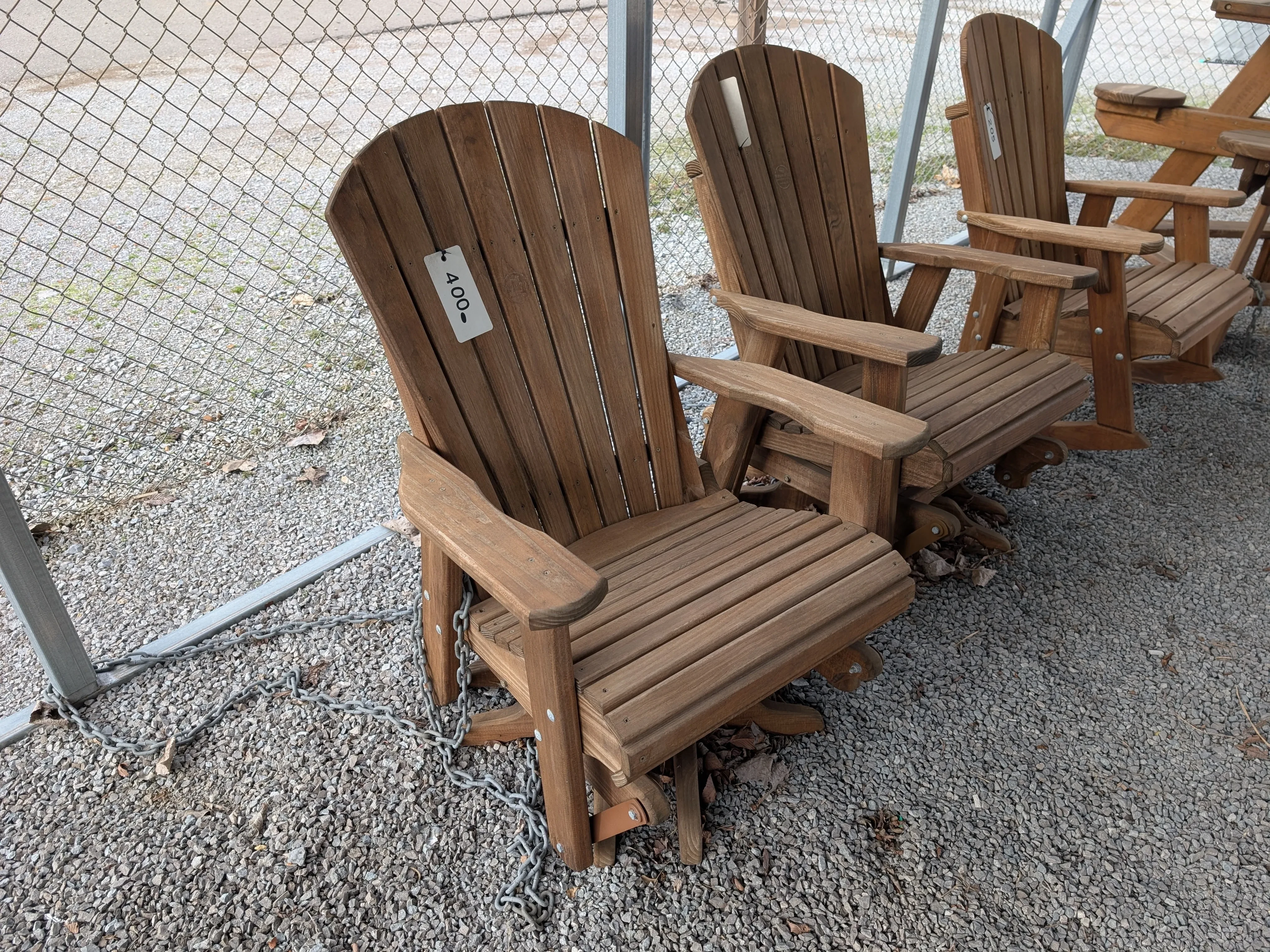 a wood stained and sealed chair next to other chairs. It can swivel 360° and glide back & forth