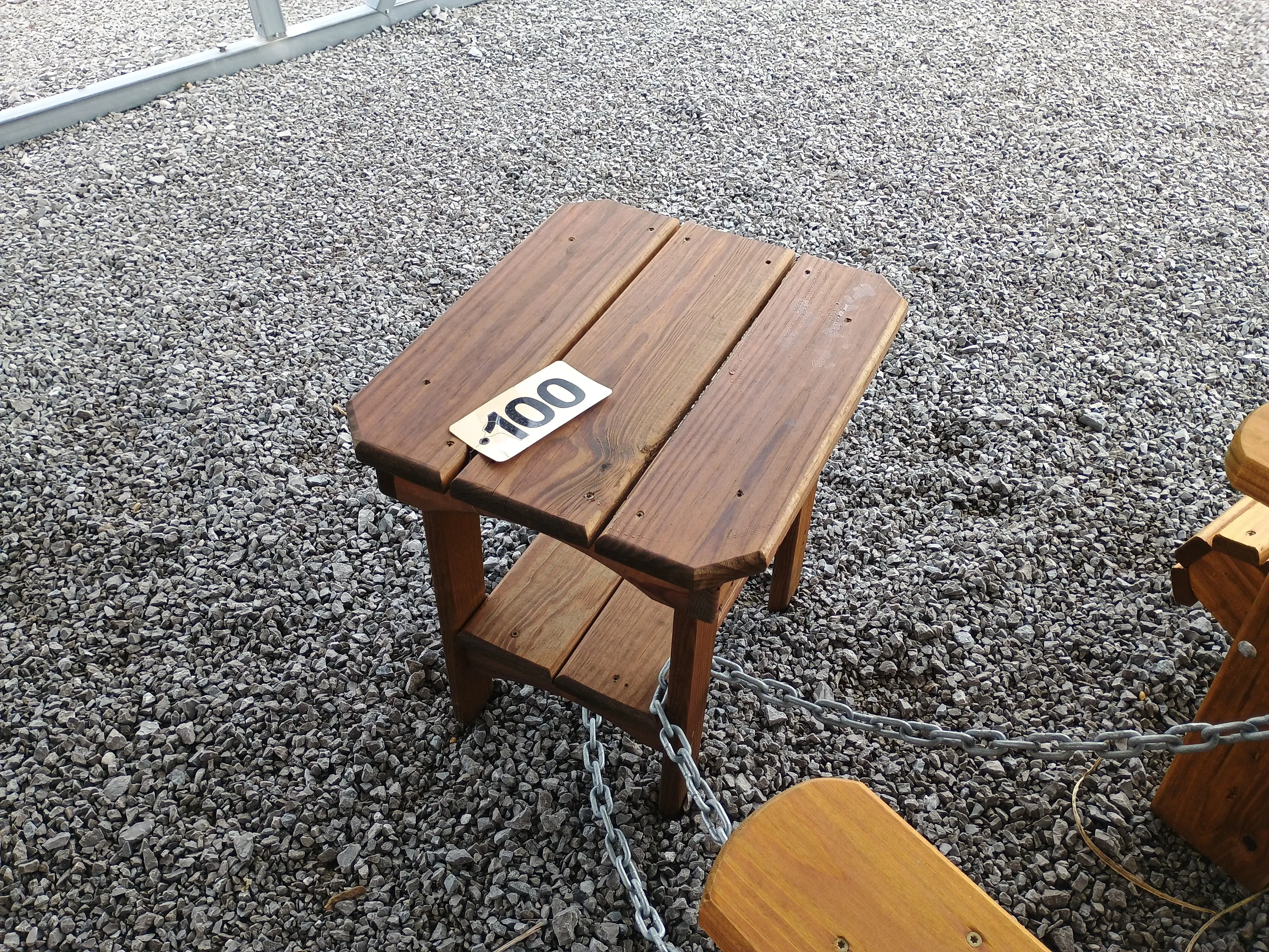 a wood table sitting in the gravel. It has a yellow price tag that says "100"