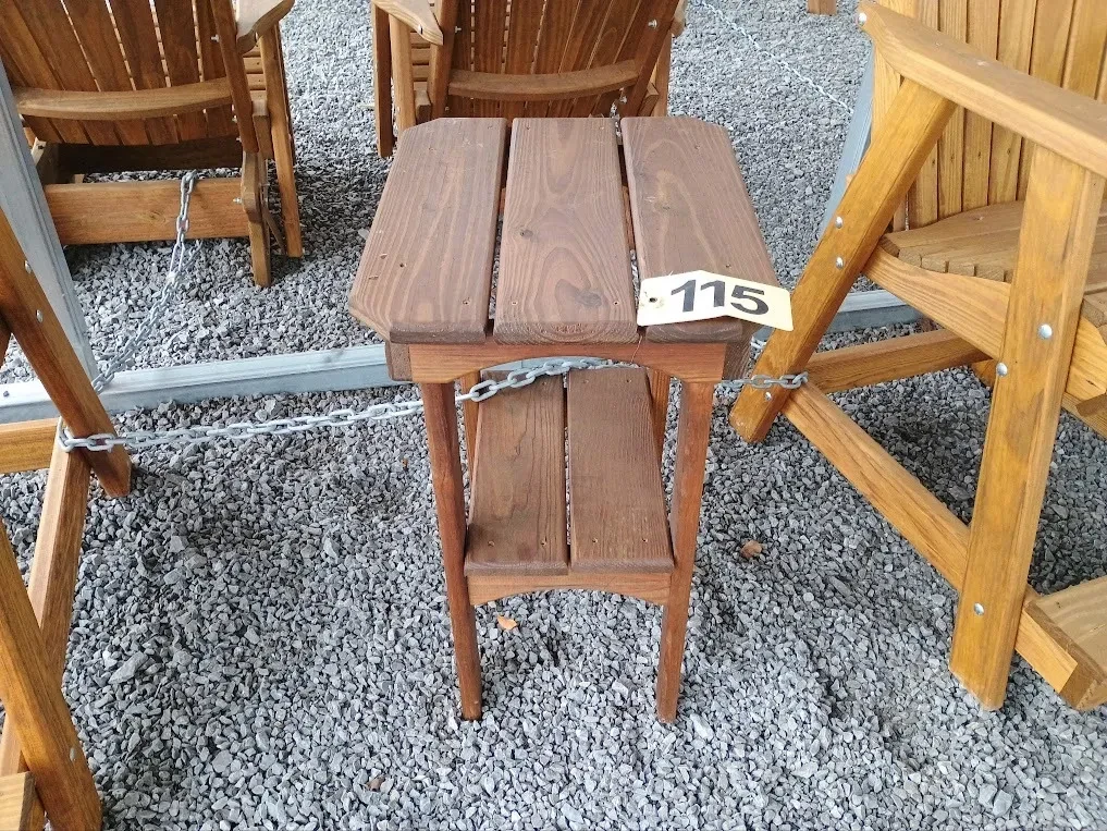 a wood stained and seal table in the gravel. It is chained up to other furniture