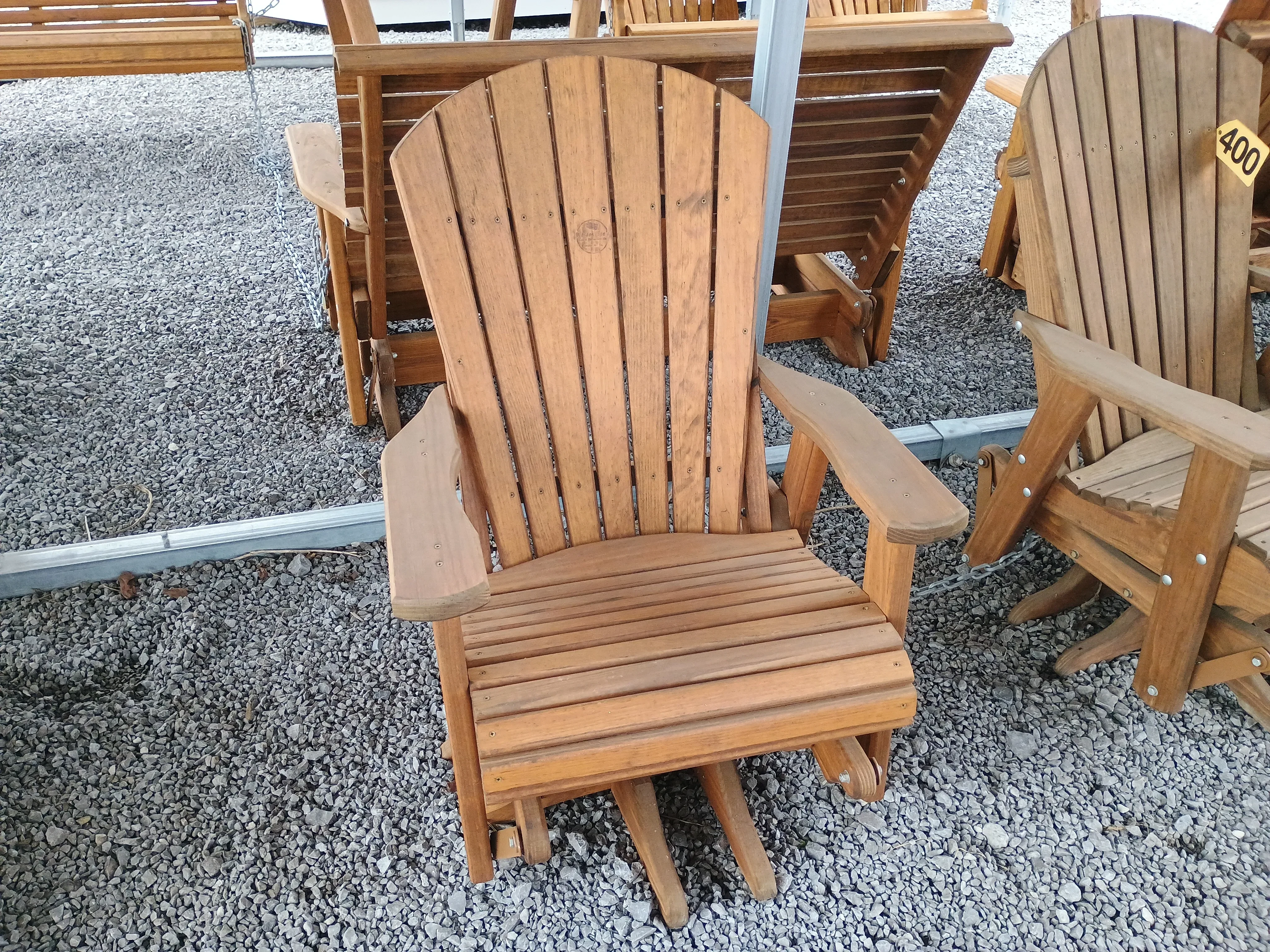 a wood chair sitting in the gravel. It can swivel 360° and glide back and forth