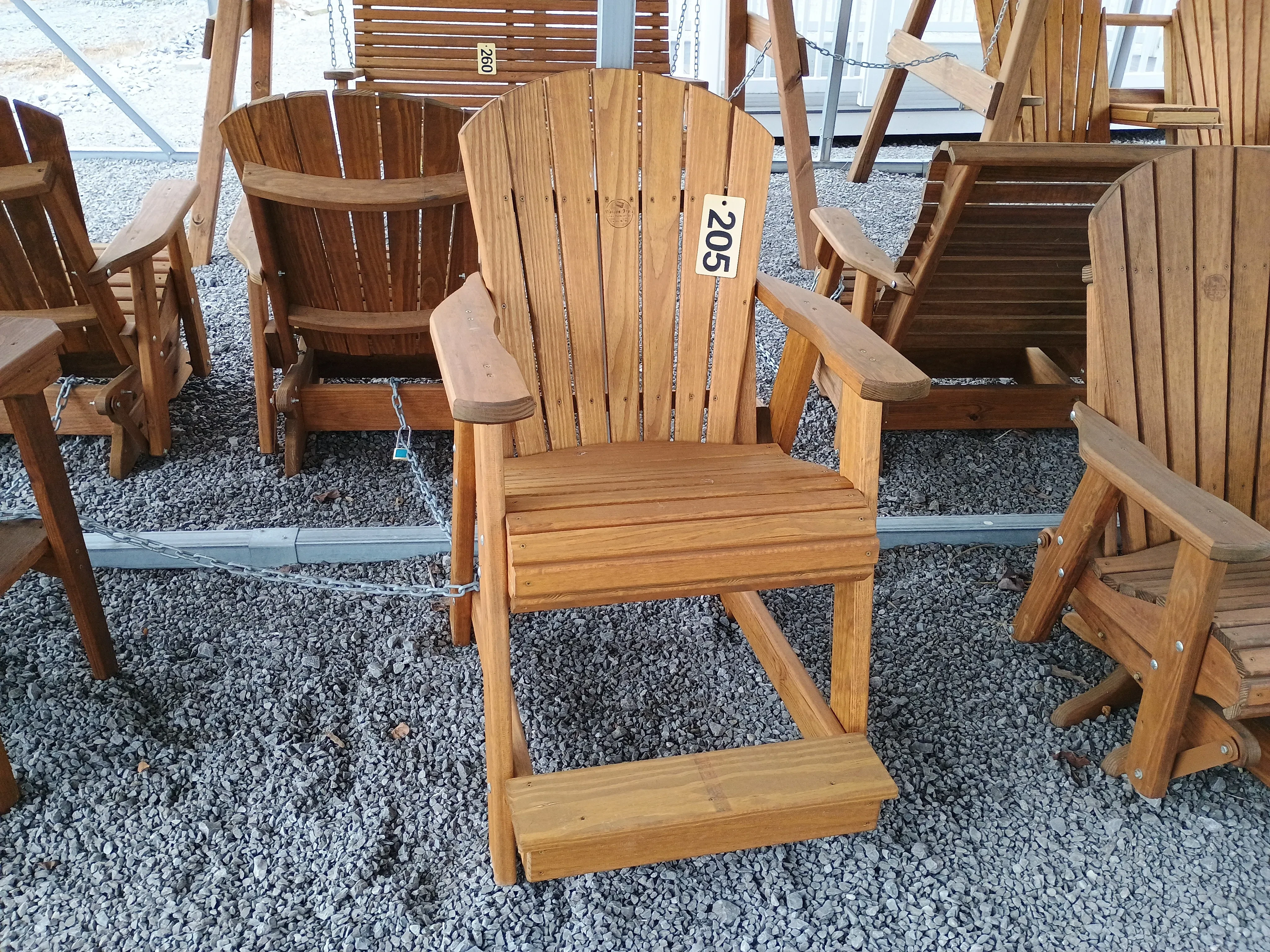 a chair sitting in the gravel. It has foot and arm rests. It is chained up to other furniture