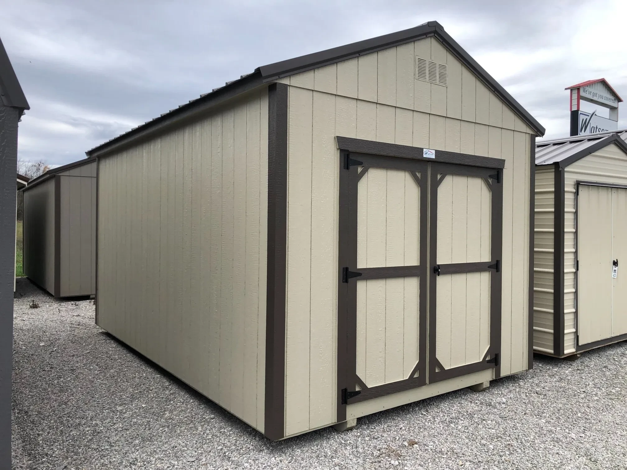 a corner view of a wooden shed painted in a light stone color