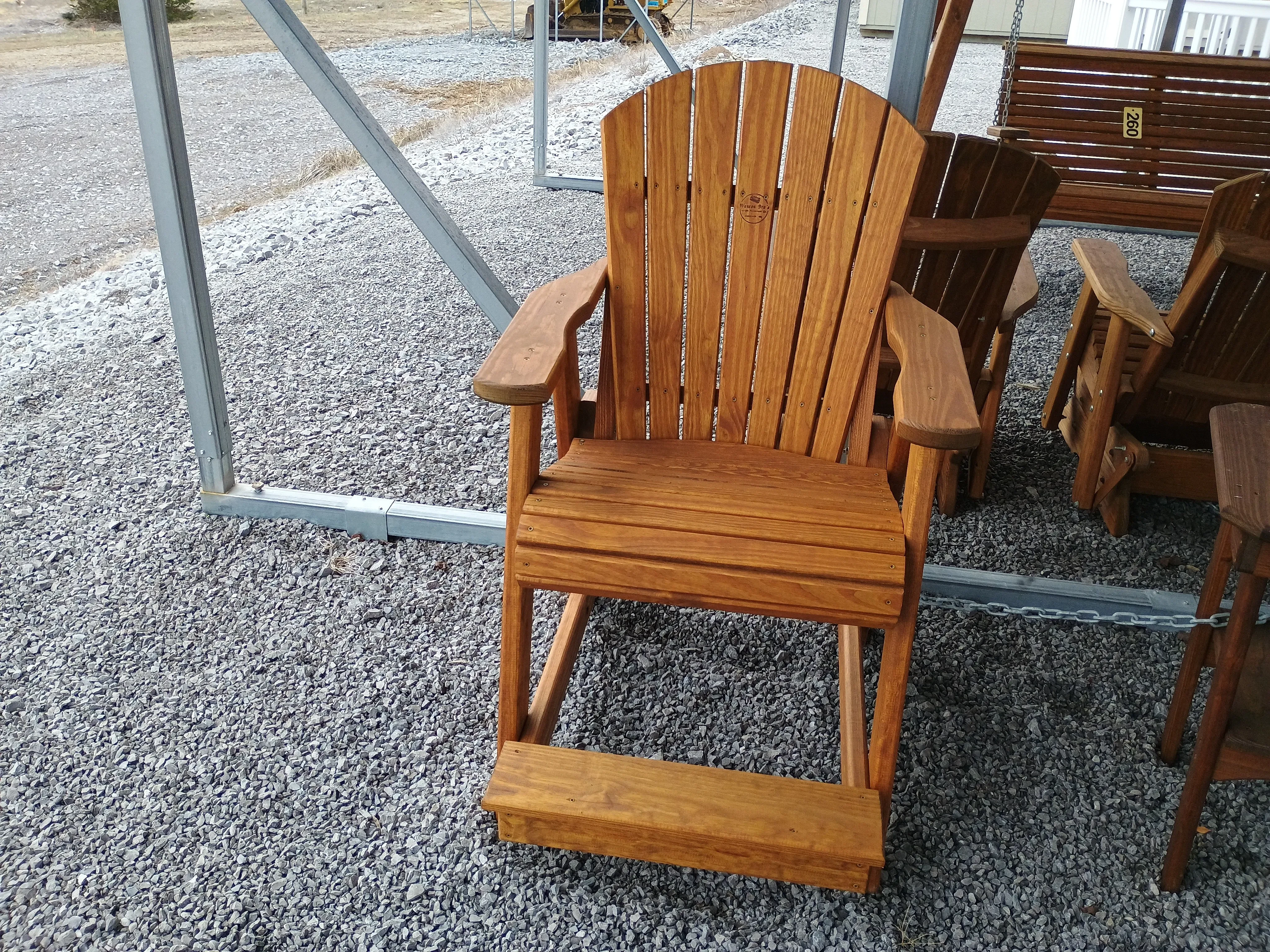 a wood chair sitting next to other furniture. It has armrests and footrests for comfort.