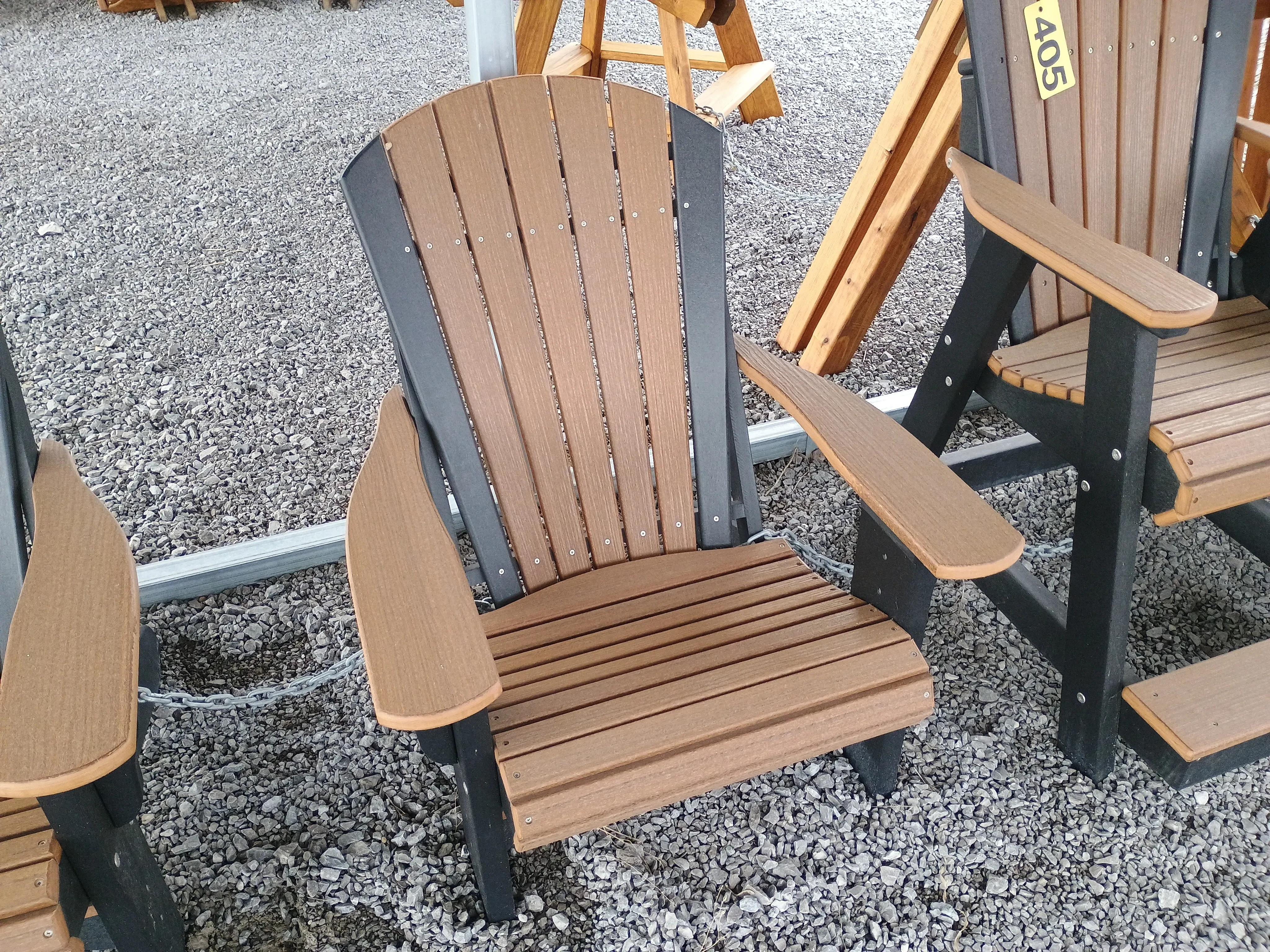 a brown and black chair sitting in the gravel. It is next to other chairs