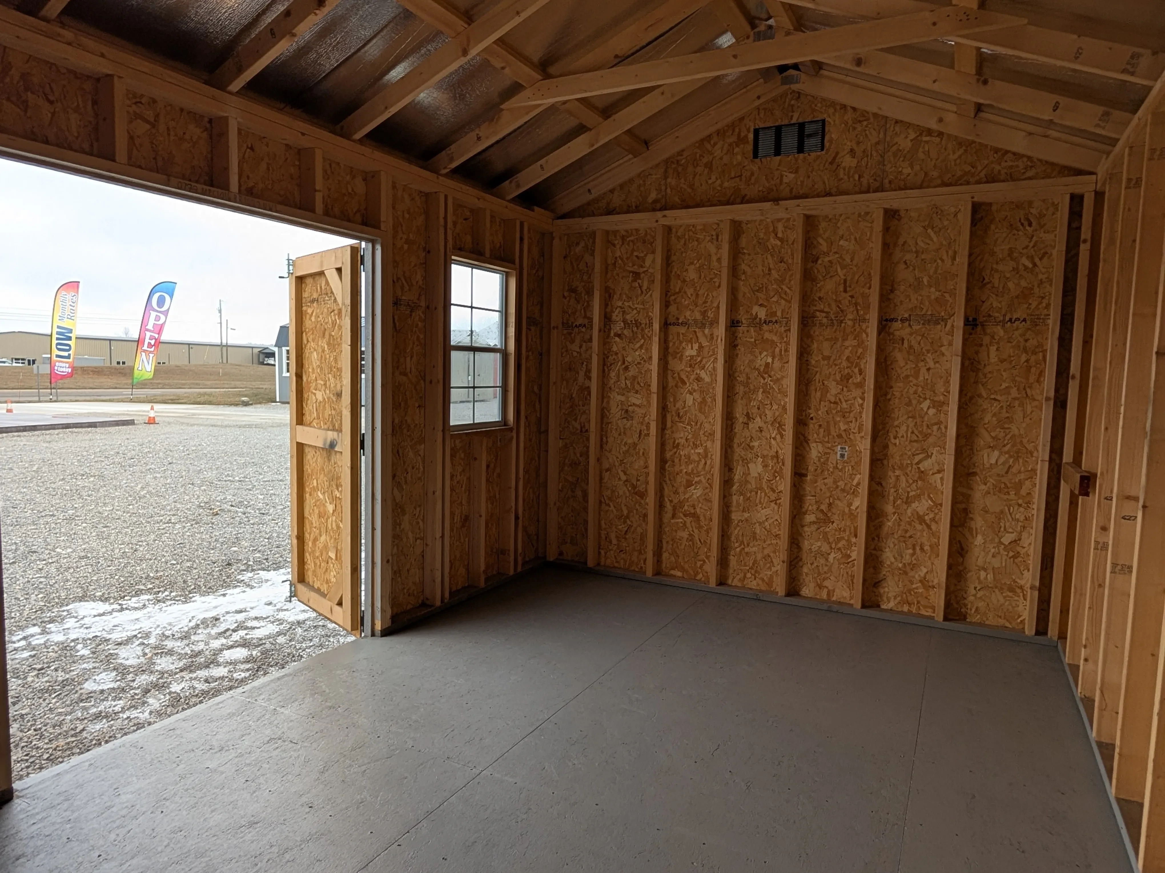 the inside of a wood garden shed looking at the left wall. There is a window in the front wall.