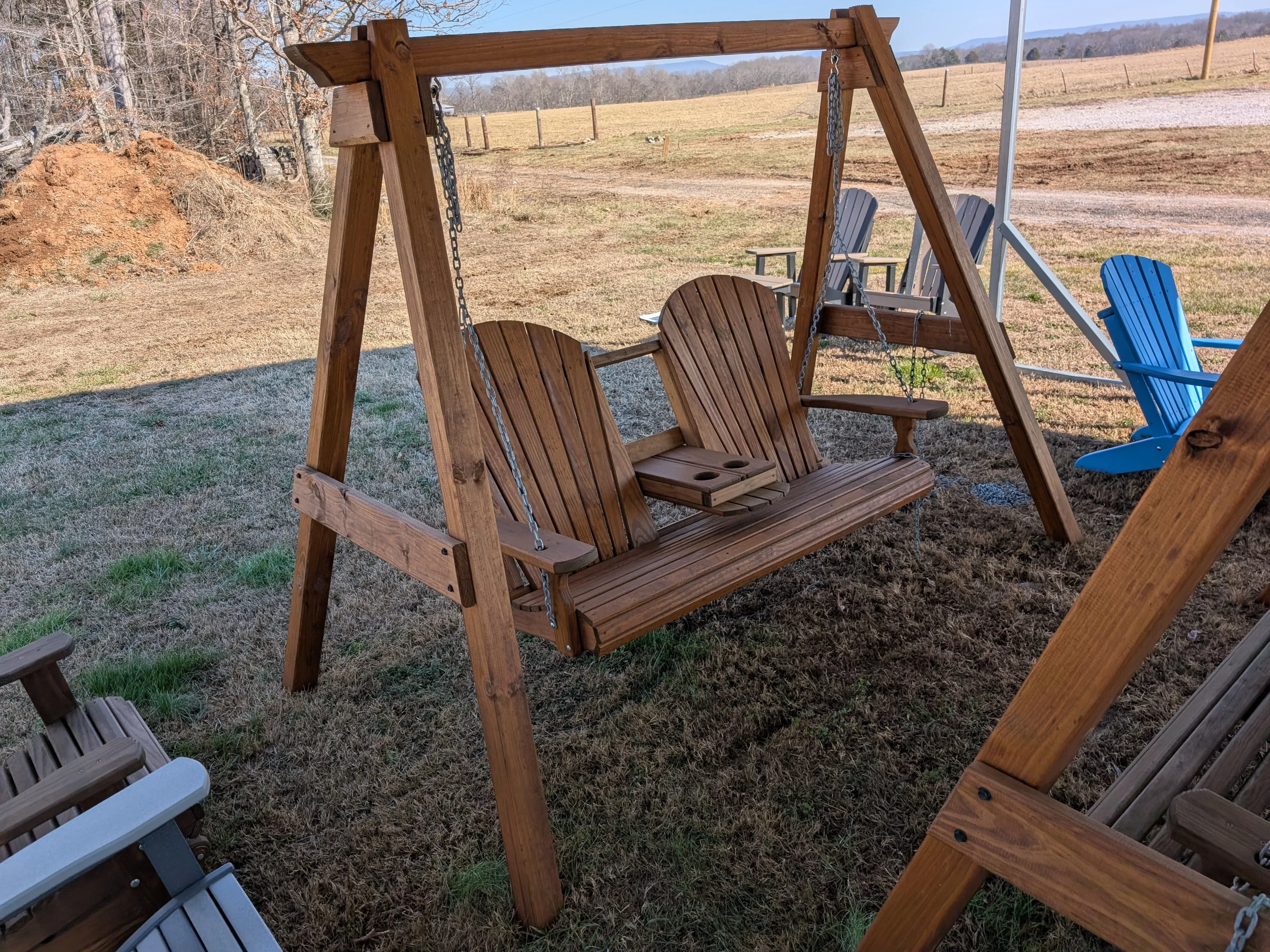 a wood bench being held up by a wooden a-frame structure. There is other furniture around