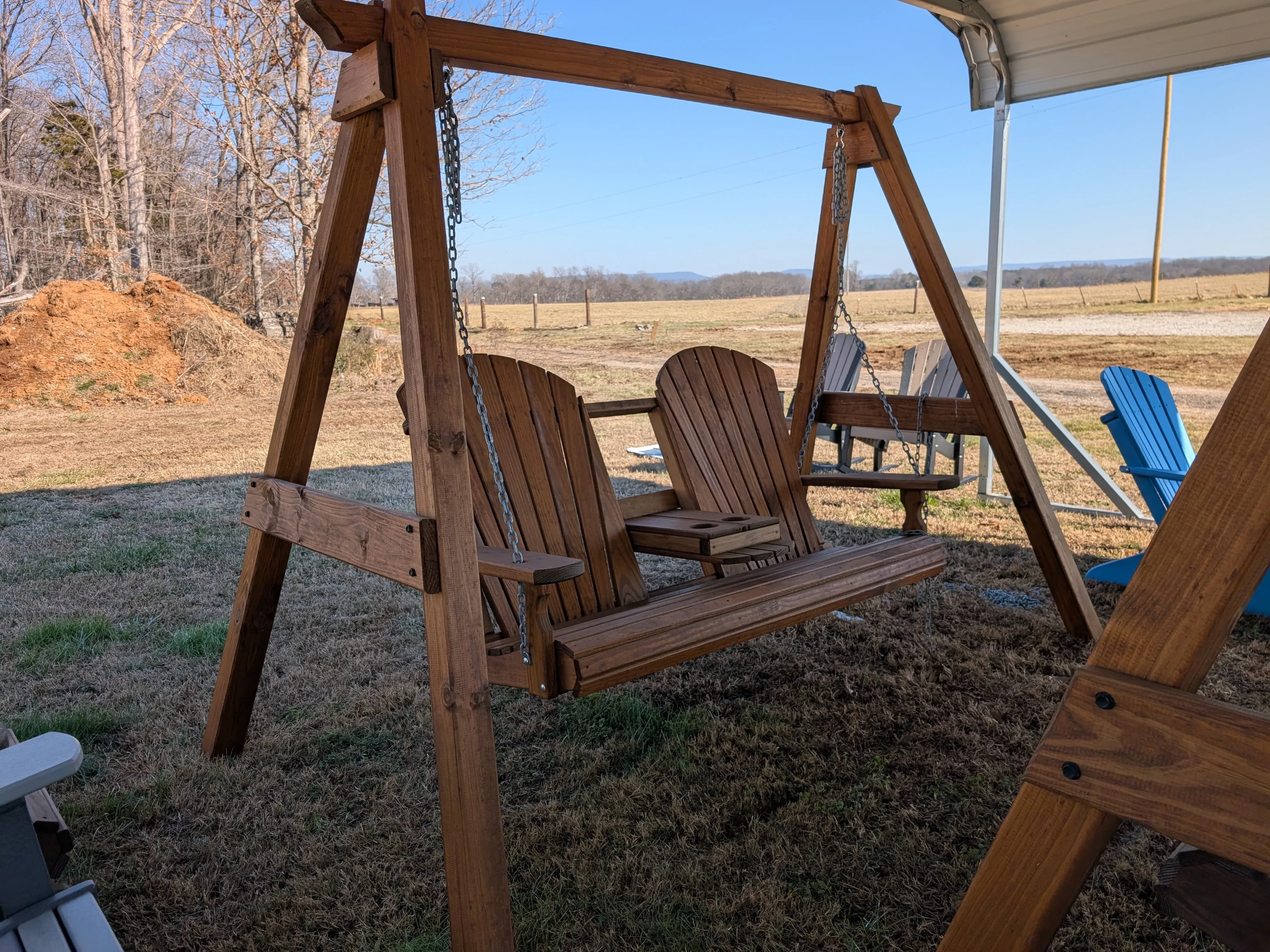 a wooden a-frame structure holding up a bench by chains