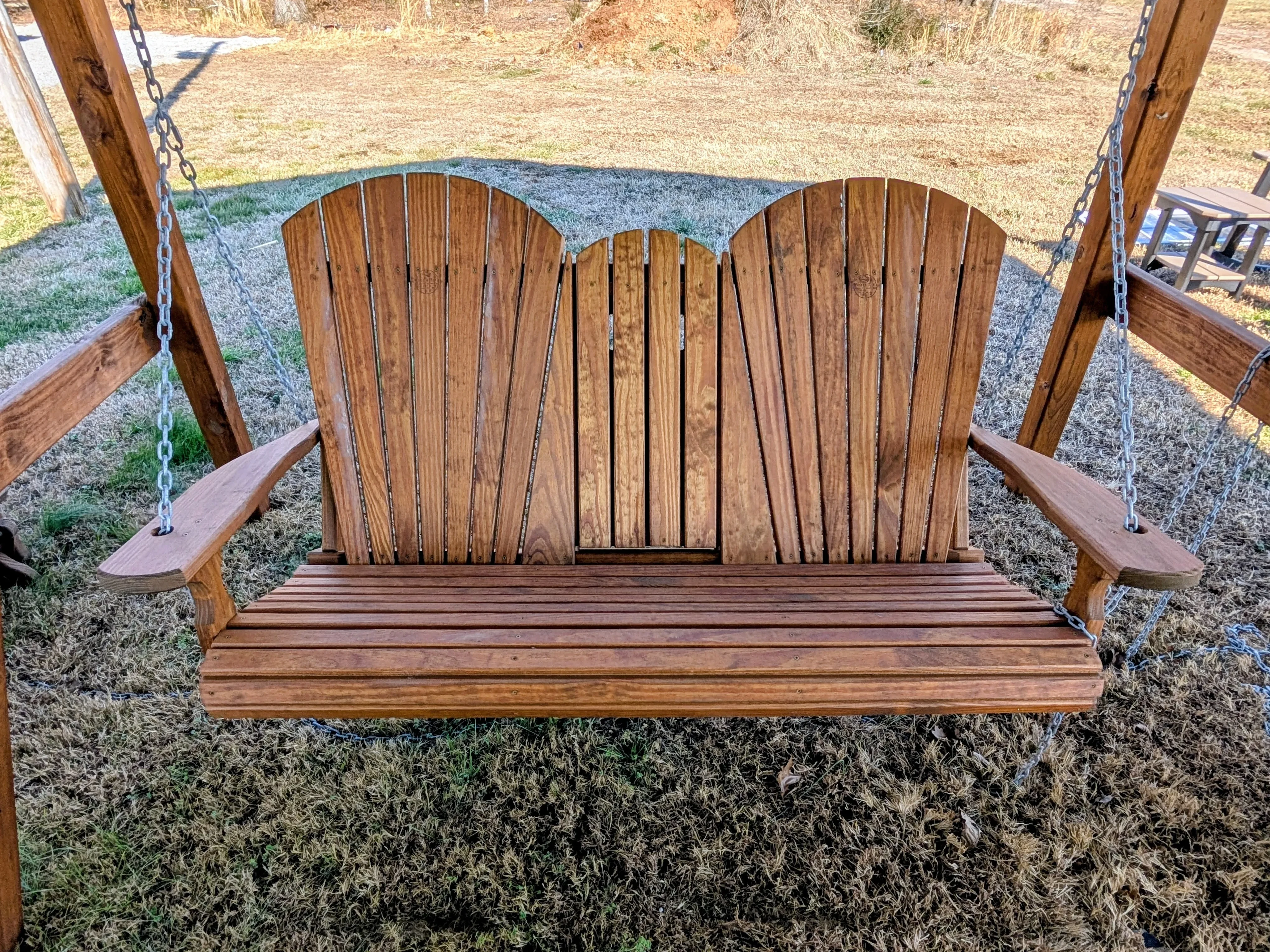 a wood swing with a center console with cupholders in the up position. It is stained and sealed