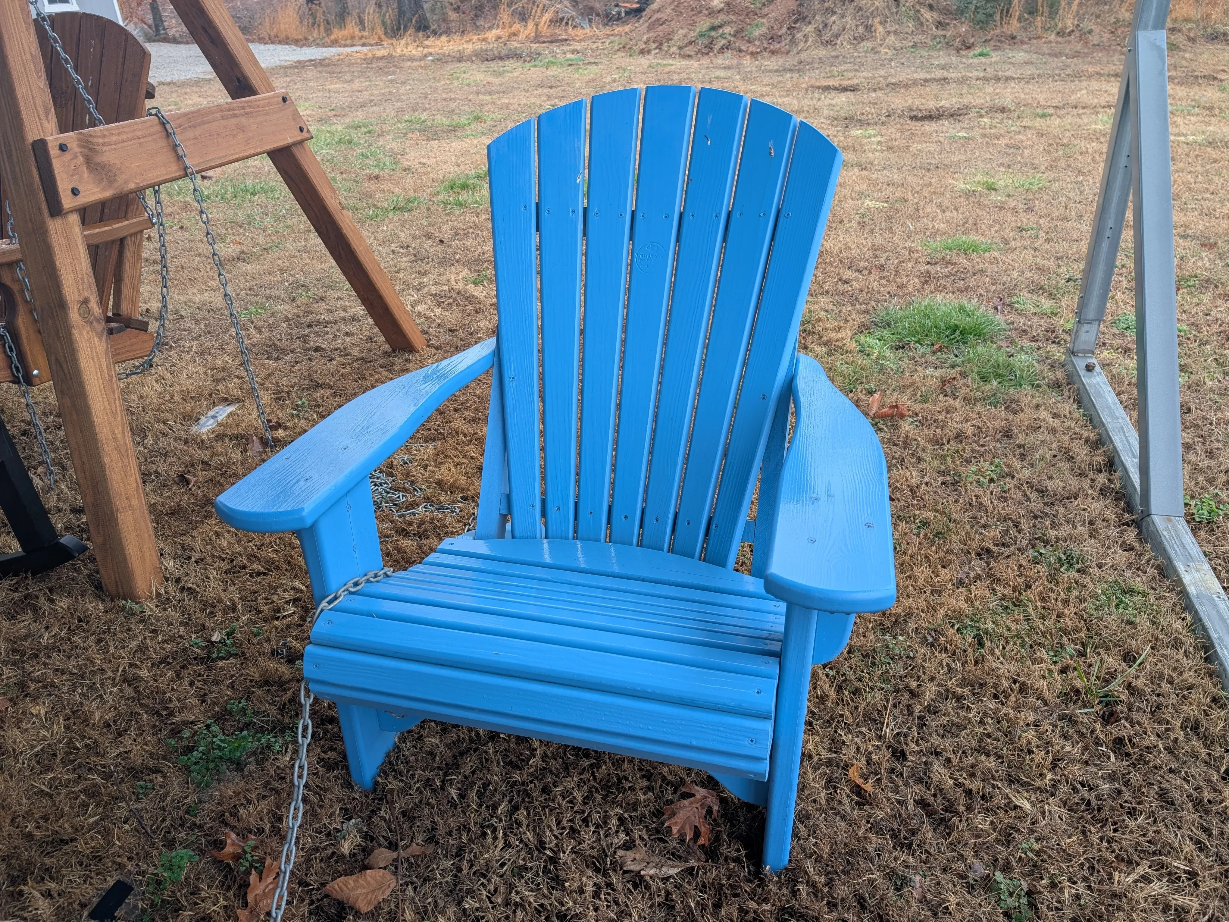 a blue chair sitting in the grass. It is chained up to other furniture
