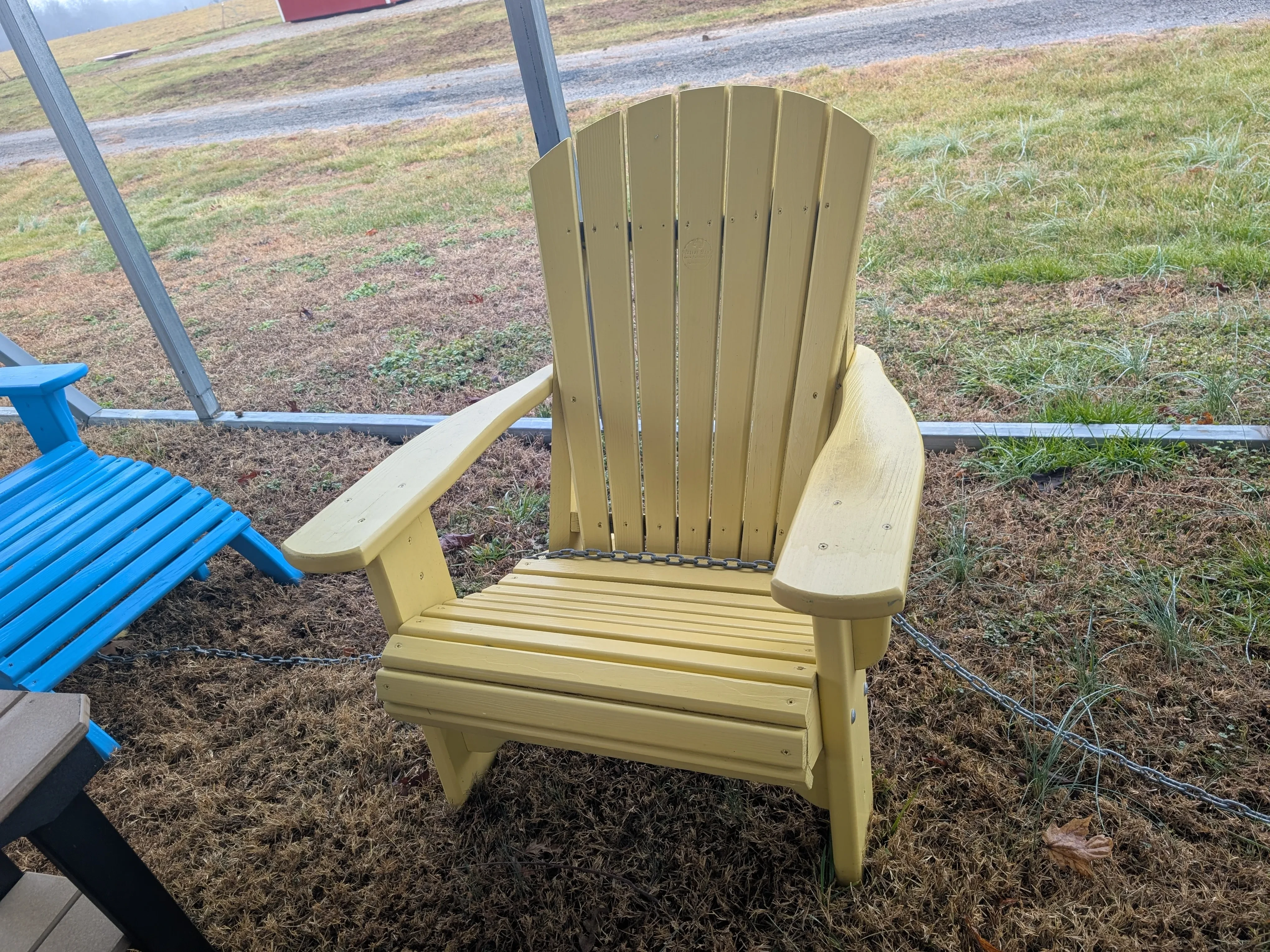 a yellow chair chained up to other furniture, it is sitting in the grass