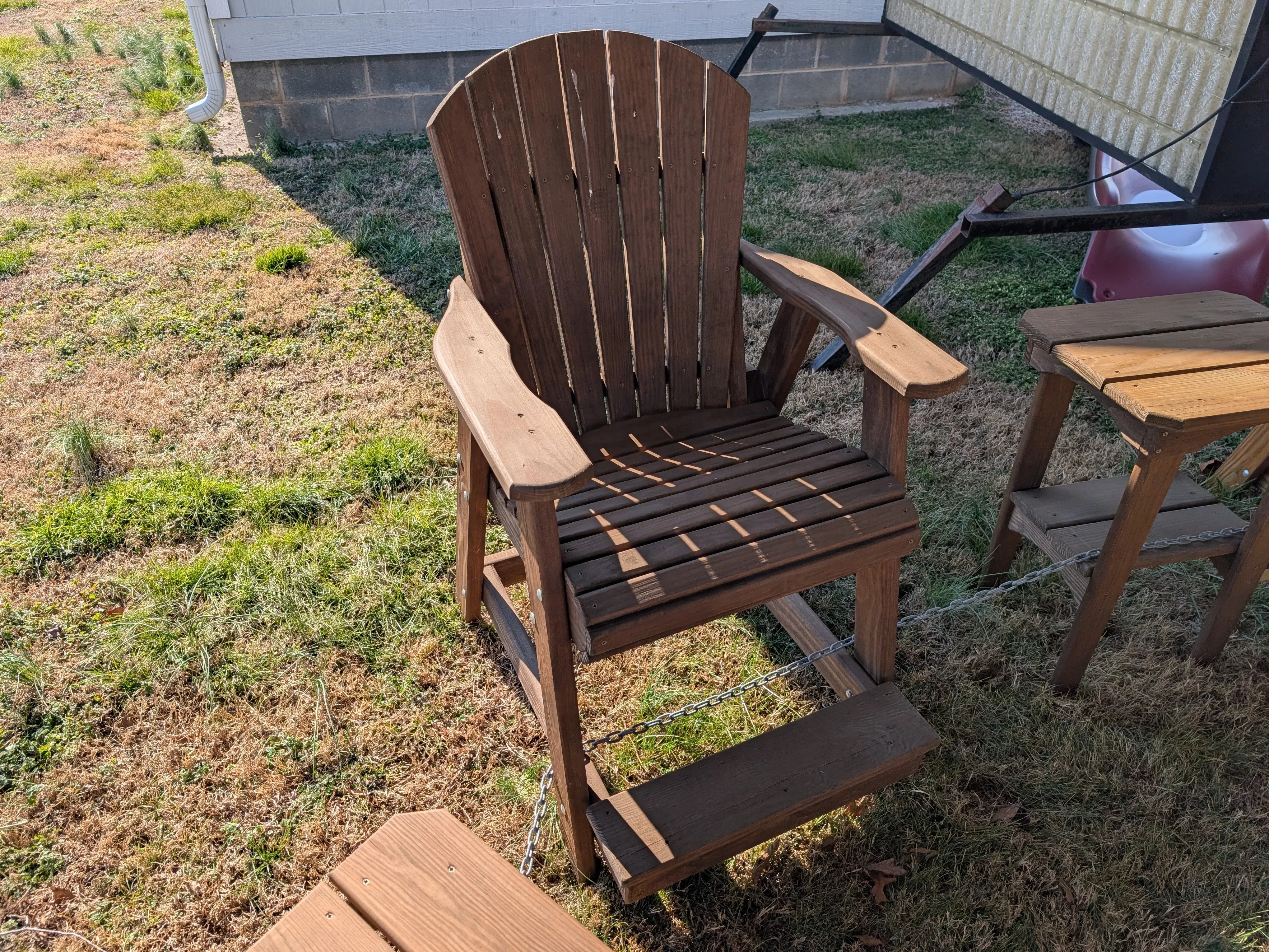 a wood chair sitting next to other furniture. It is chained up and has been properly stained and sealed