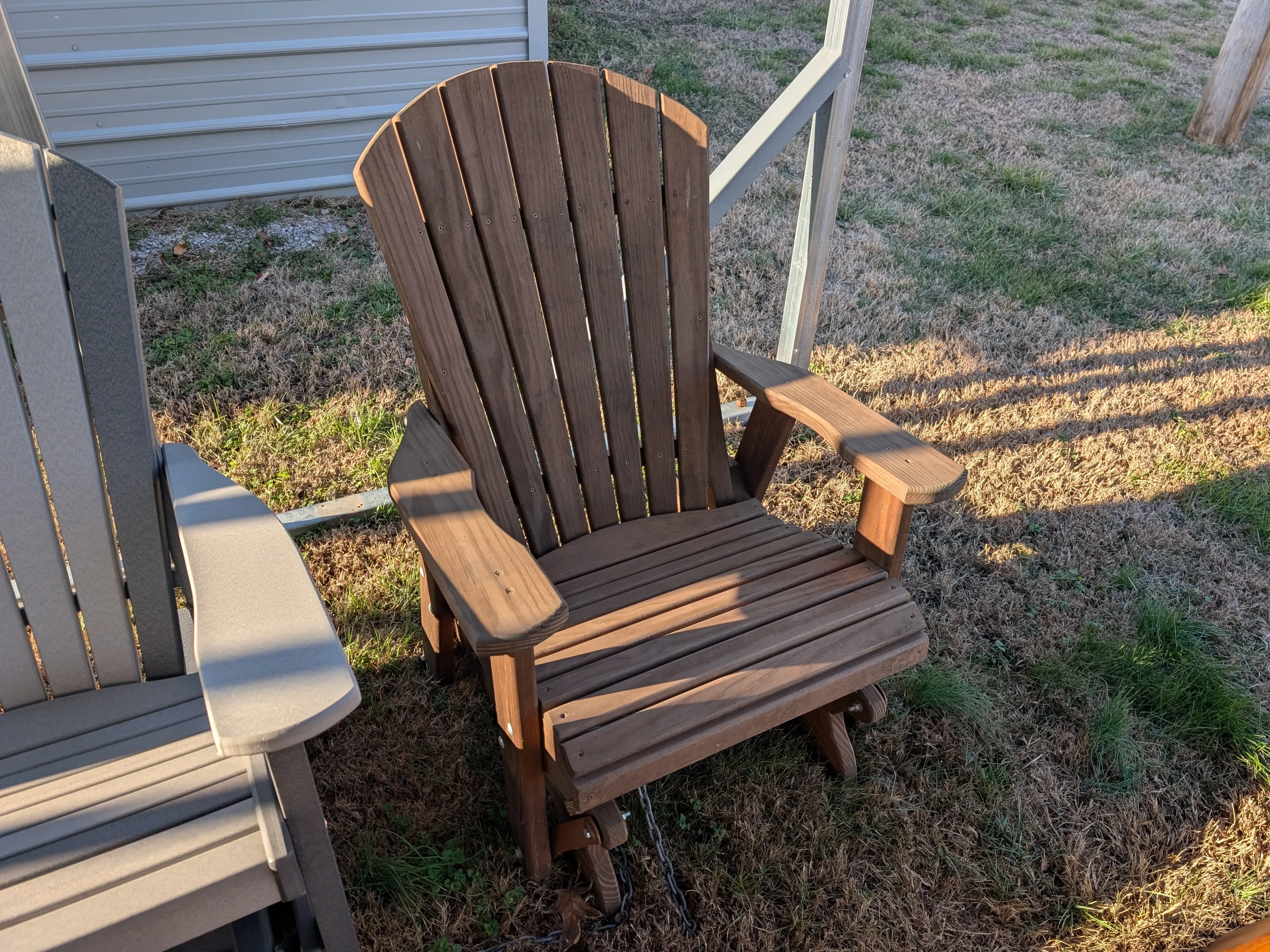 a wood chair sitting in the grass. It is professionally stained and sealed brown
