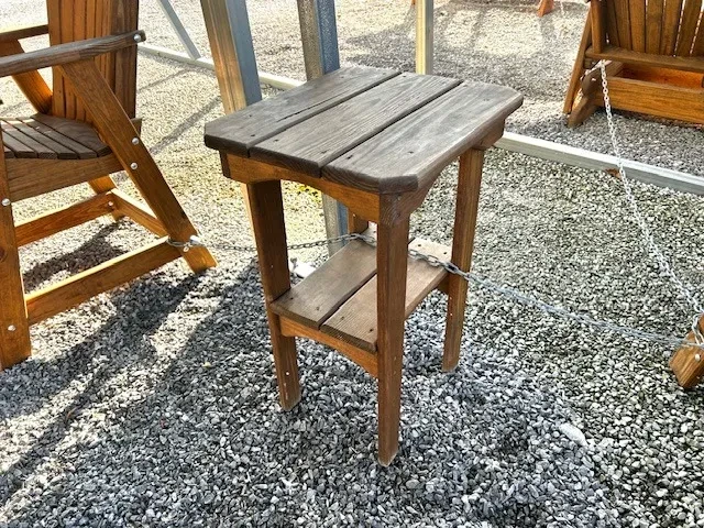 a wood table sitting in the gravel. It has two tabletops