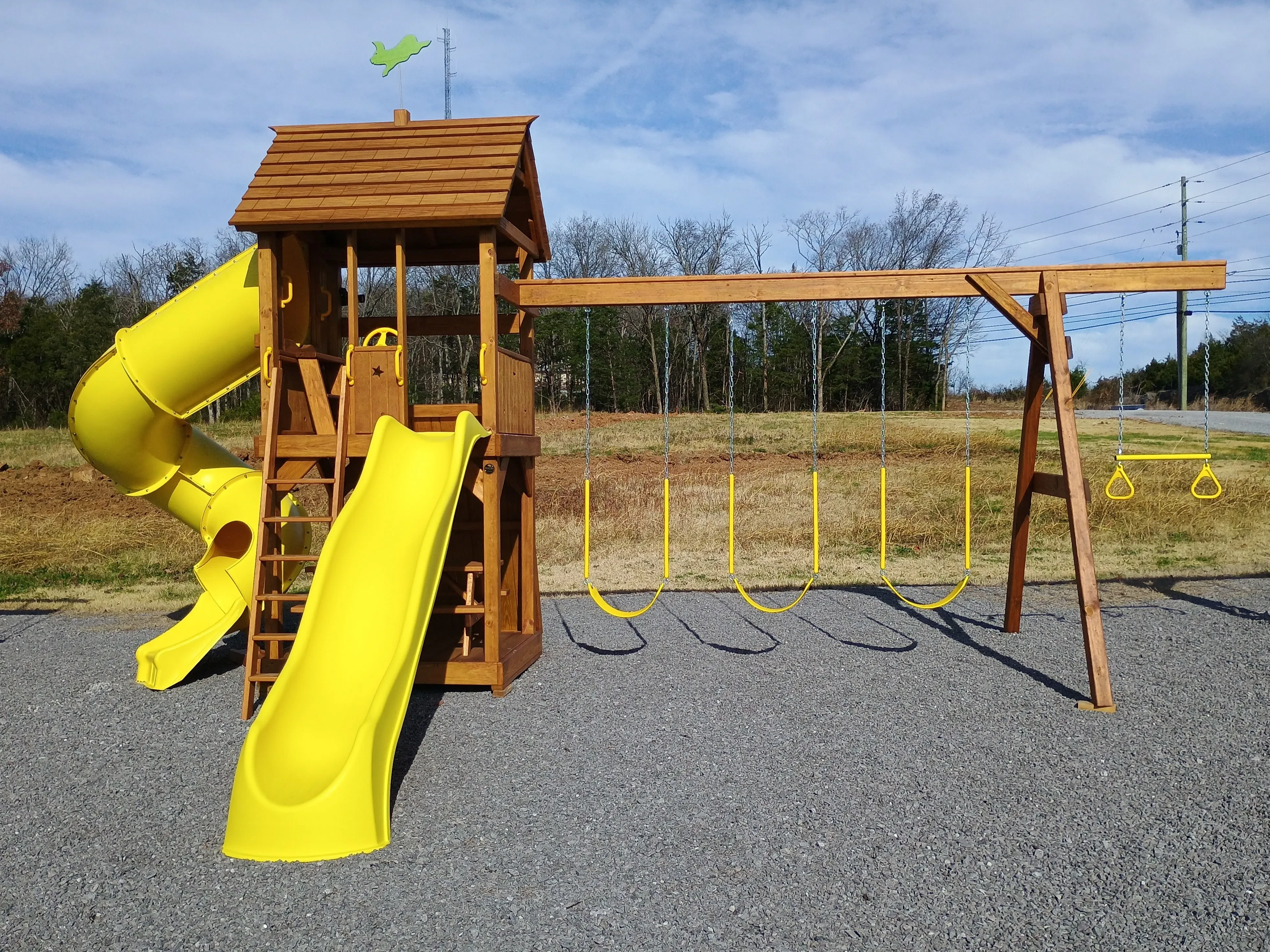 wood stained and sealed playset with two yellow slides and three yellow swings