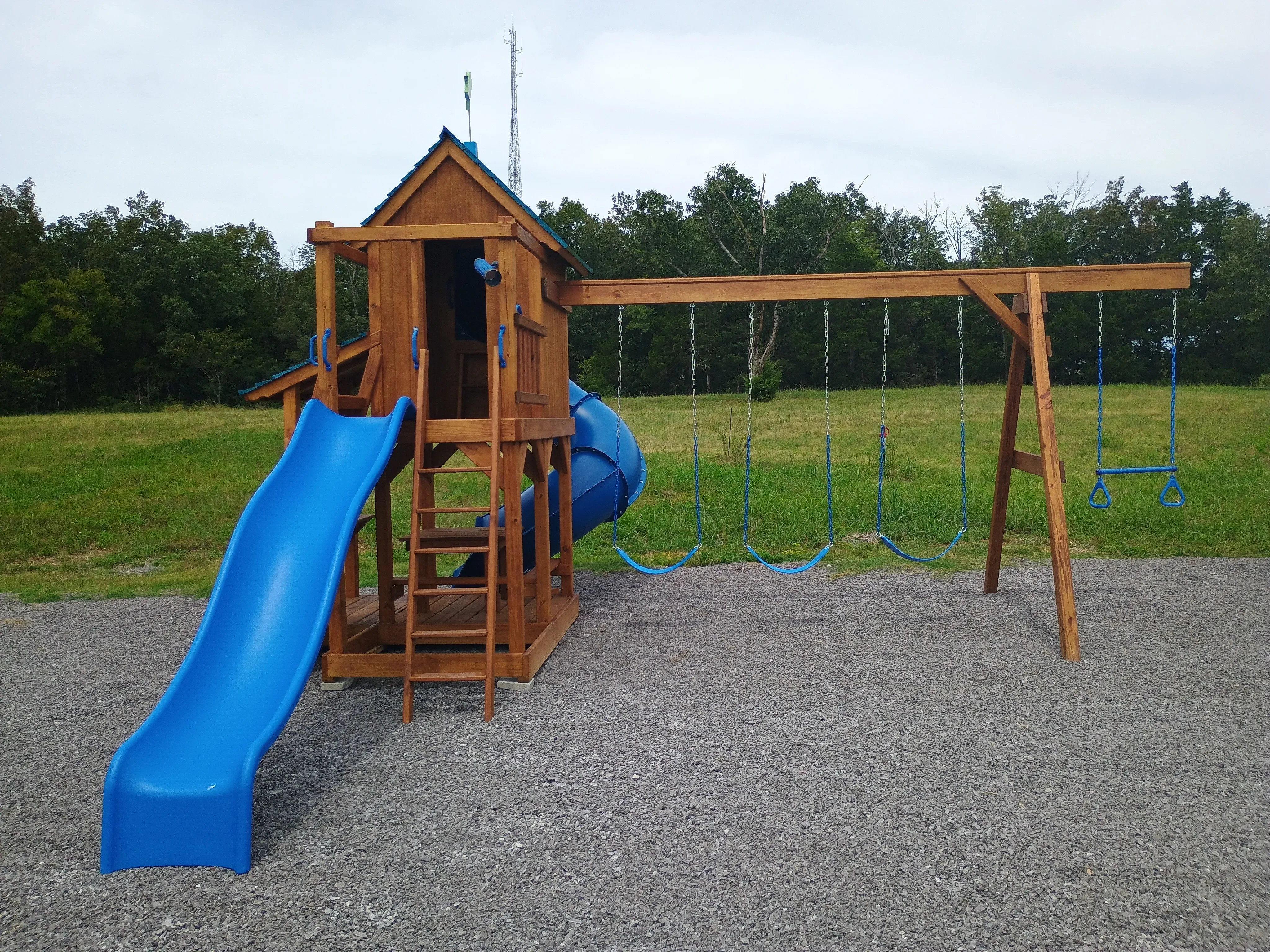 a wood playset. It is stained and sealed professionally. It has two blue slides and three blue swings