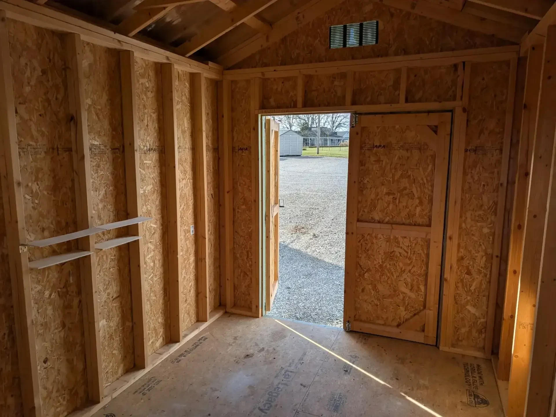 The inside of a wood shed showing double doors that are open.