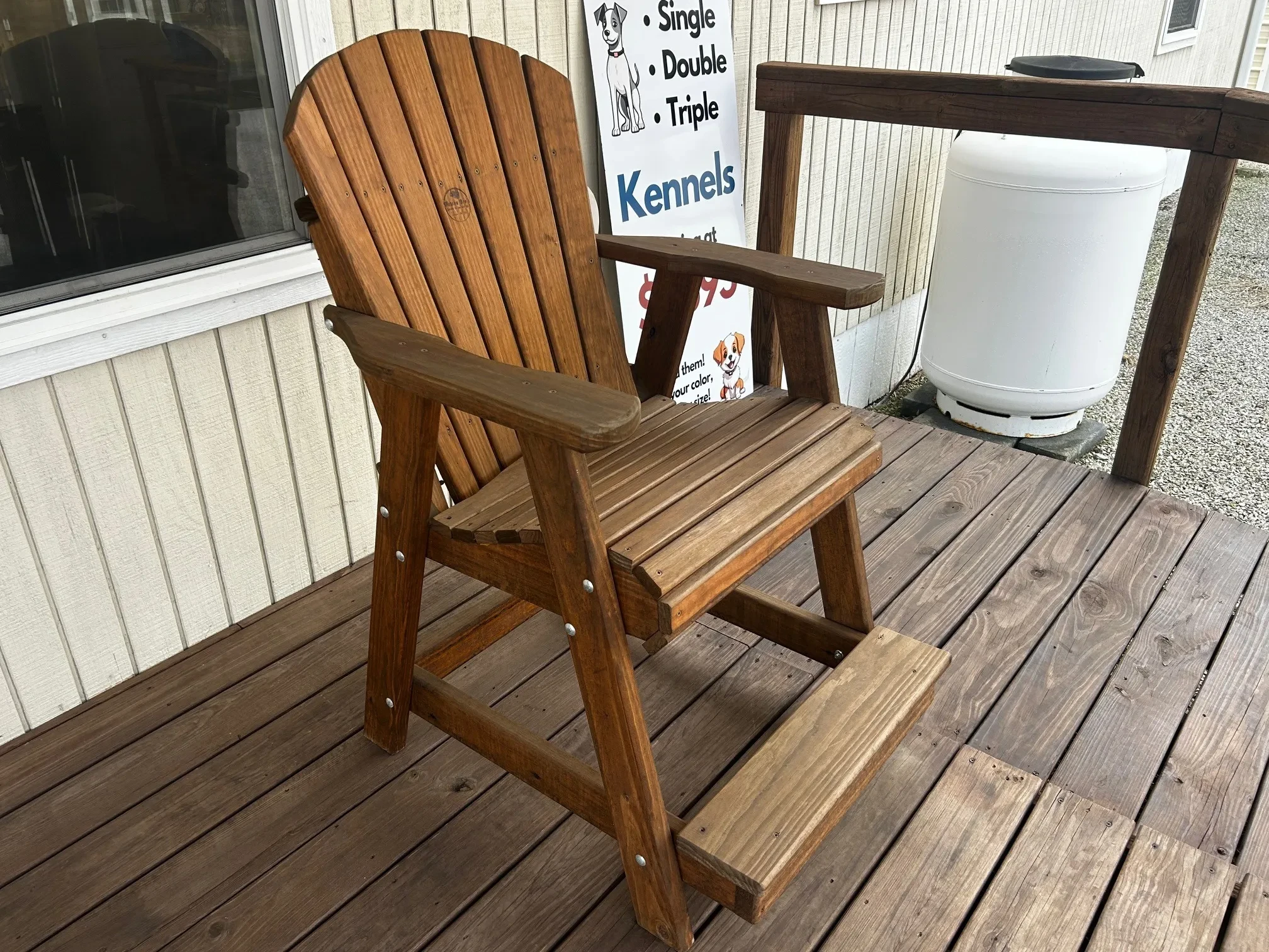 a stained and sealed wood chair with armrests and footrests sitting on a porch
