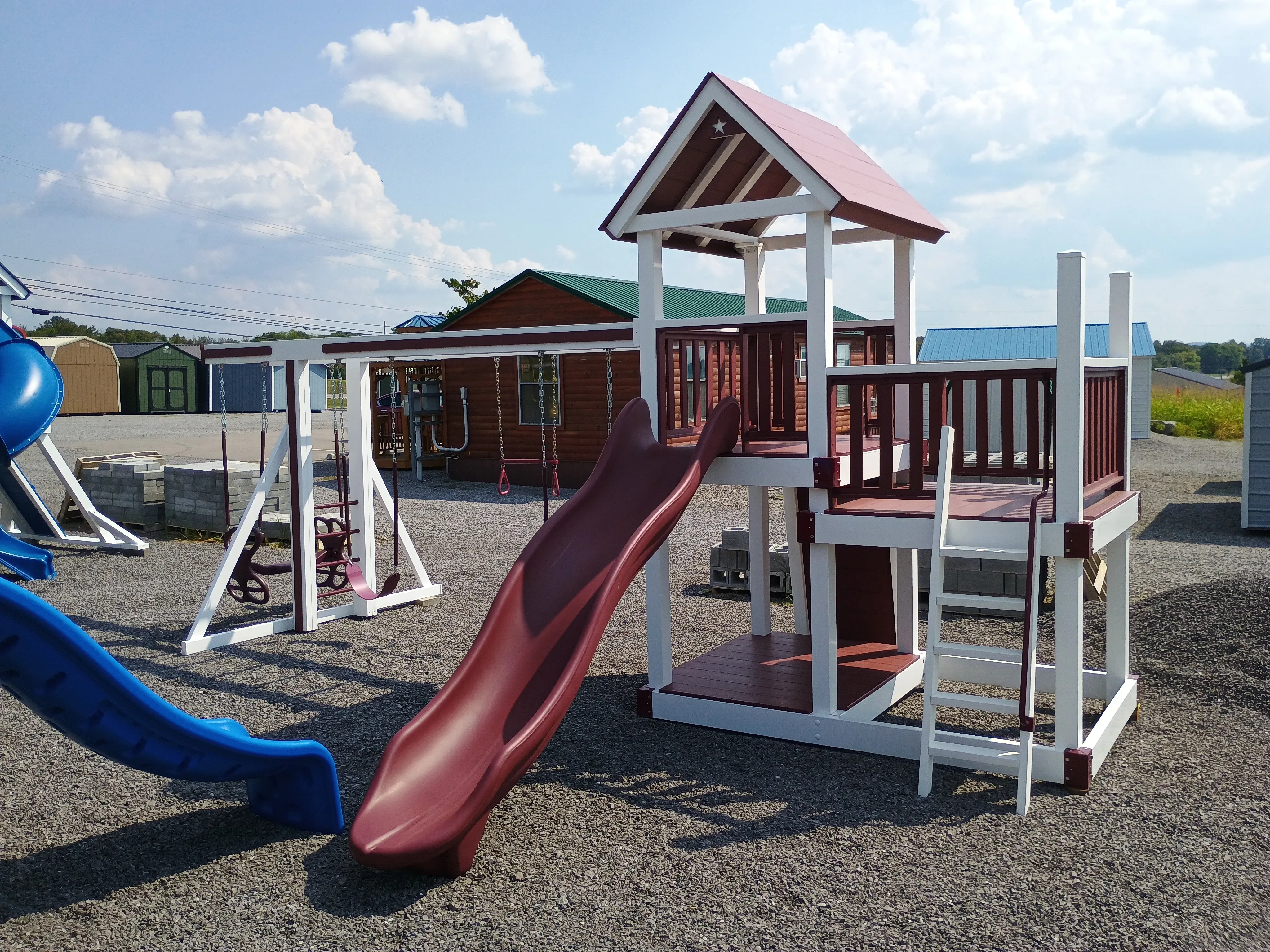 the back side of a white vinyl playset. It has a red slide and red railings