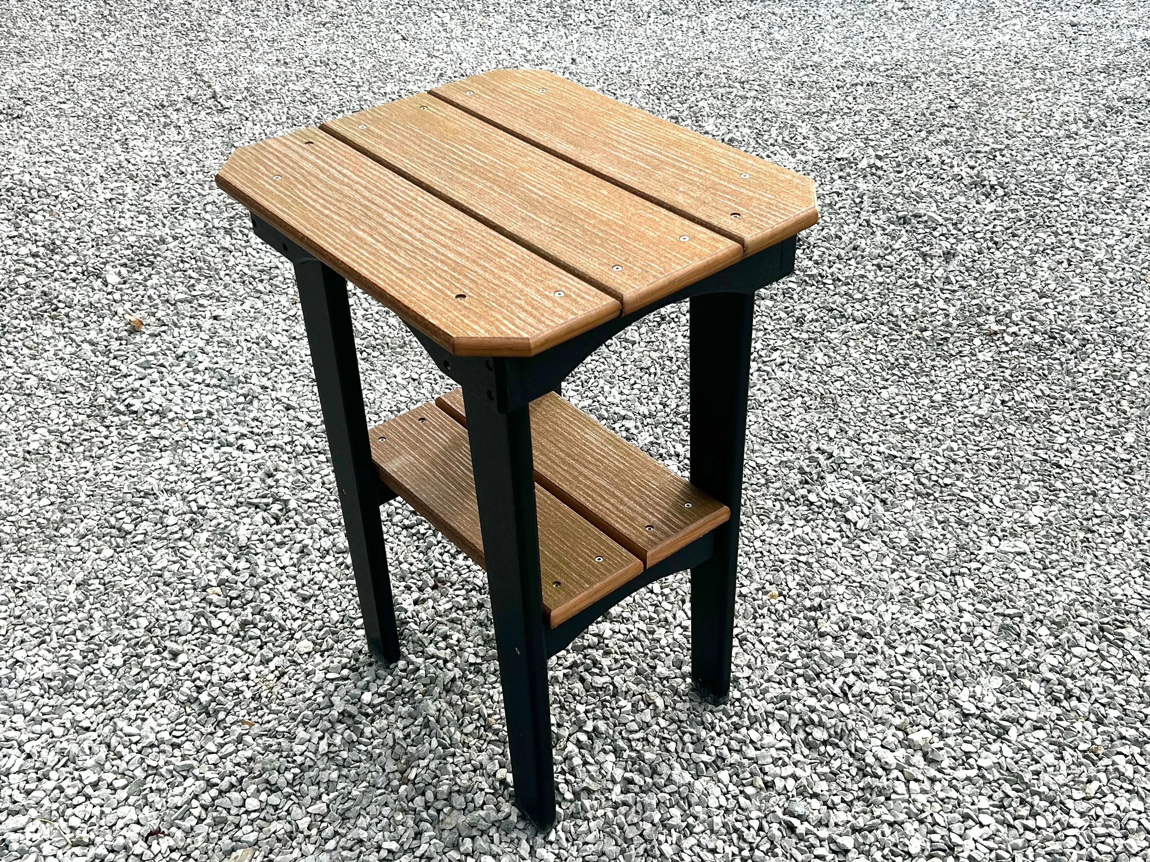 a polywood table with a tapletop and another smaller tabletop underneath. It is standing in the gravel