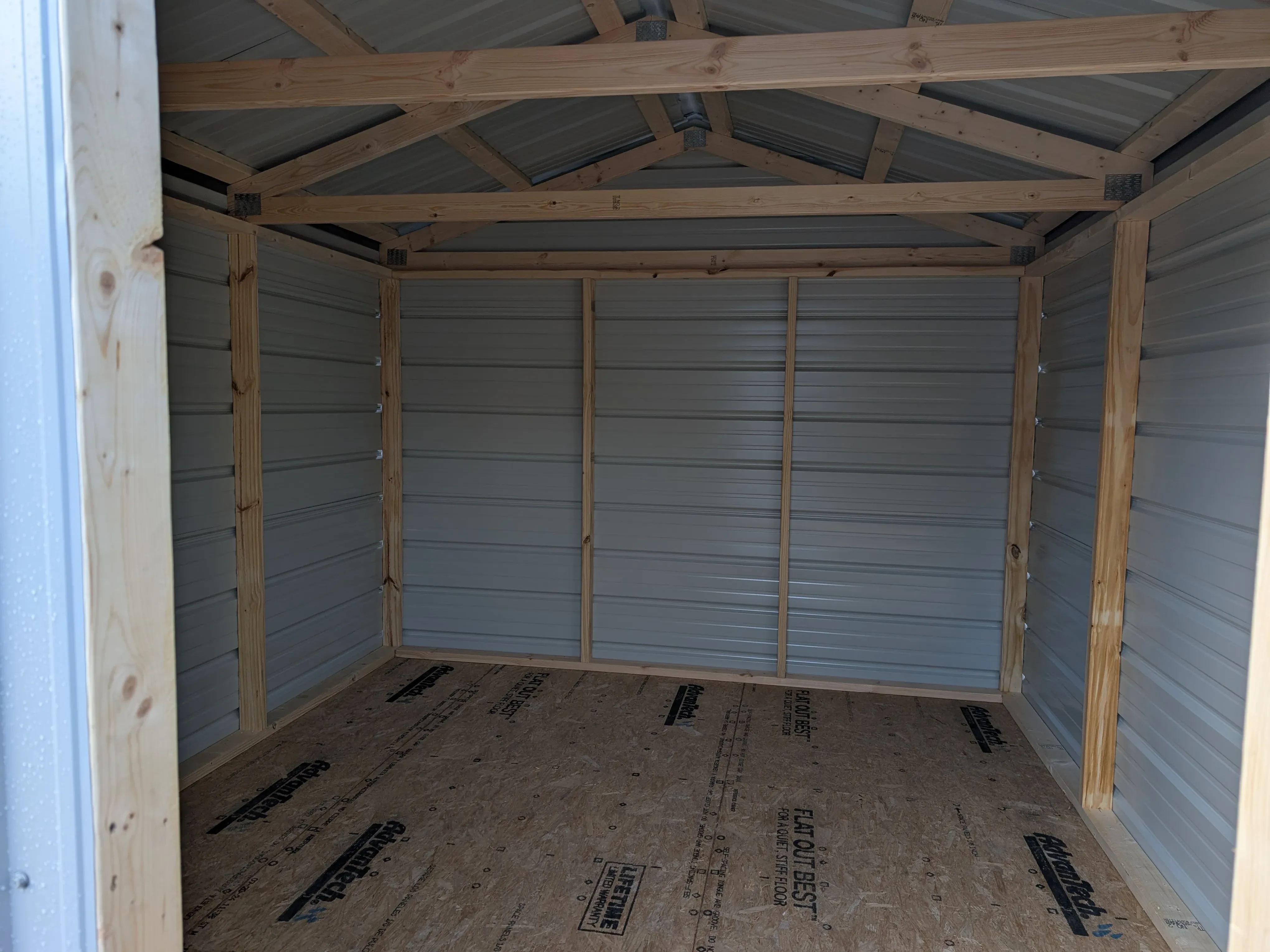 inside a metal utility shed looking at the back wall. You can see the framing and solid floor