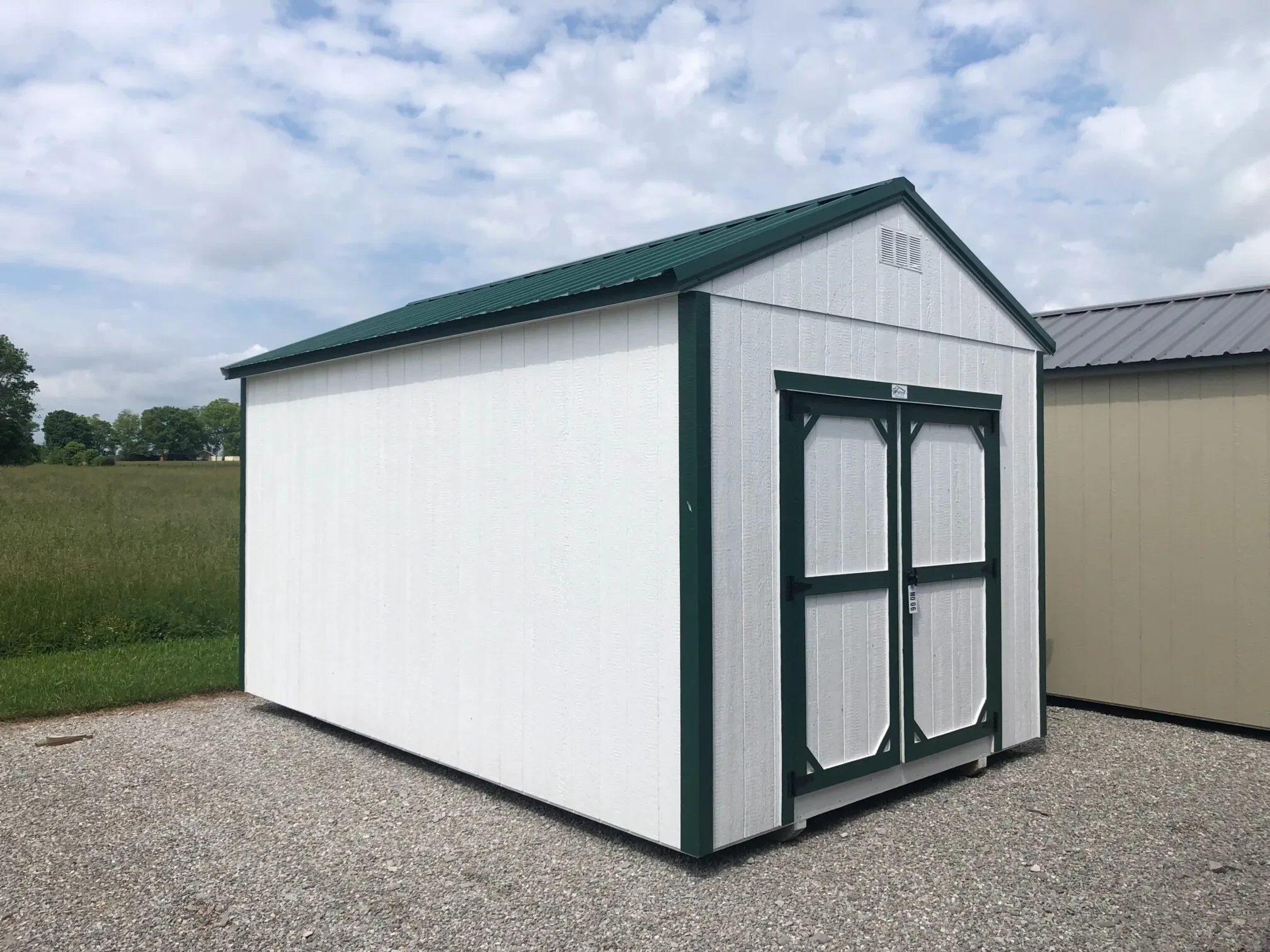 The front corner view of a green and white shed with double doors