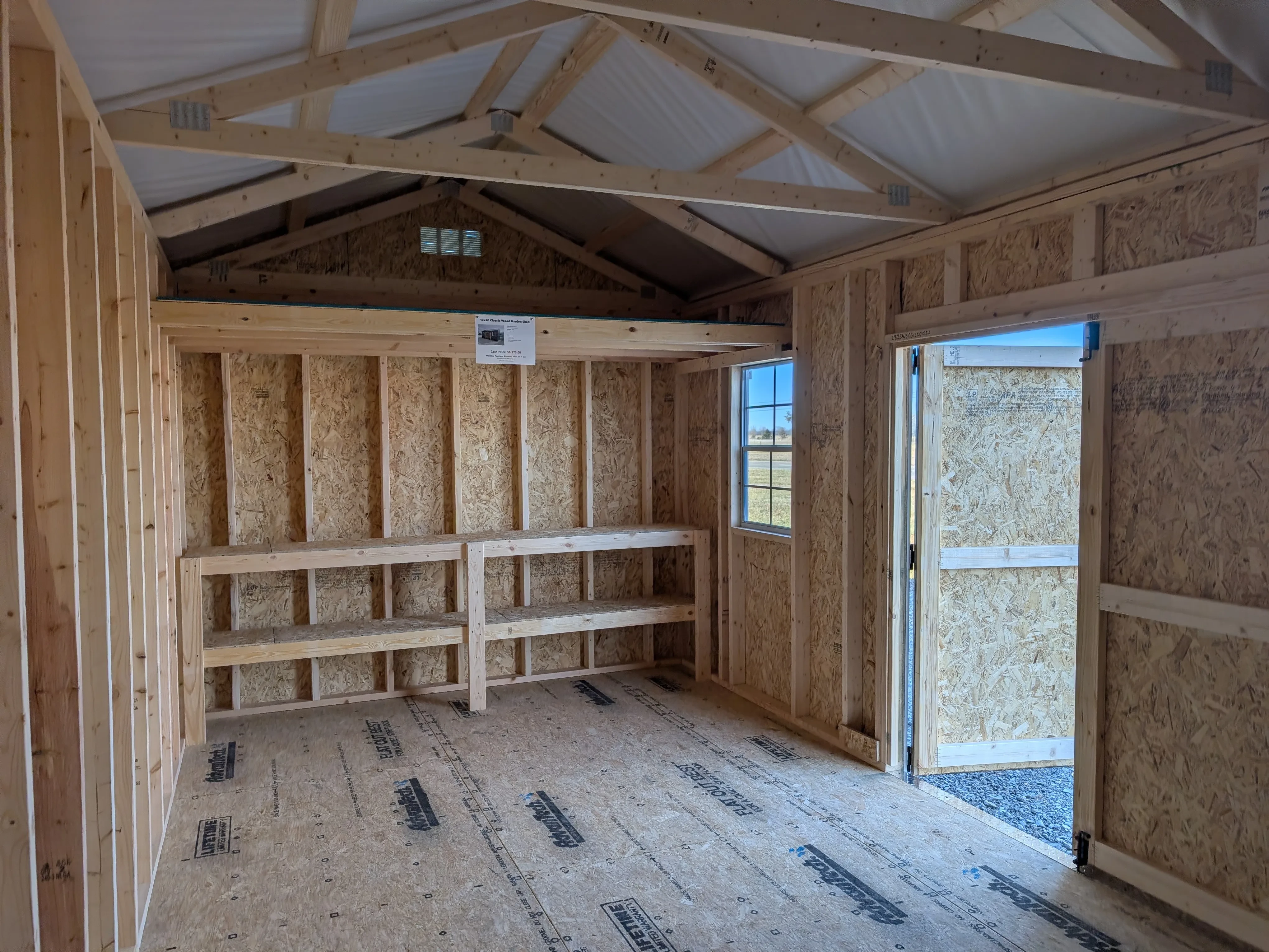 inside a wood garden shed looking at the right wall. It has a 4' loft and double shelves underneath the loft.