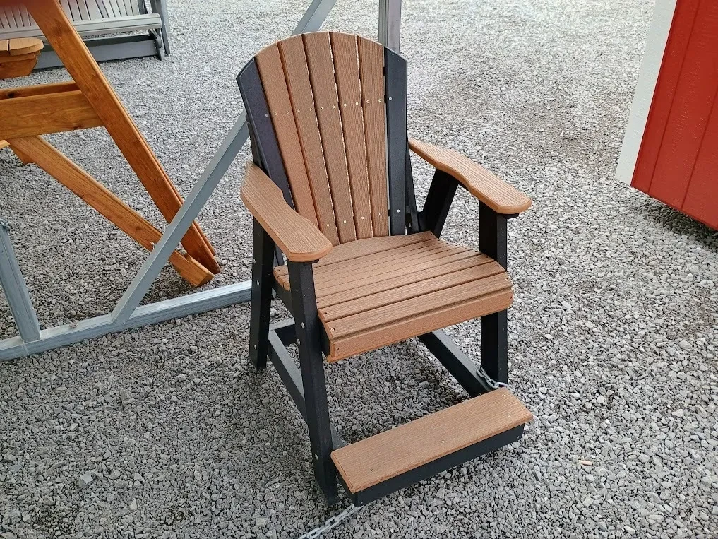 a two toned chair that is brown and black sitting in the gravel. It has armrests and footrests.