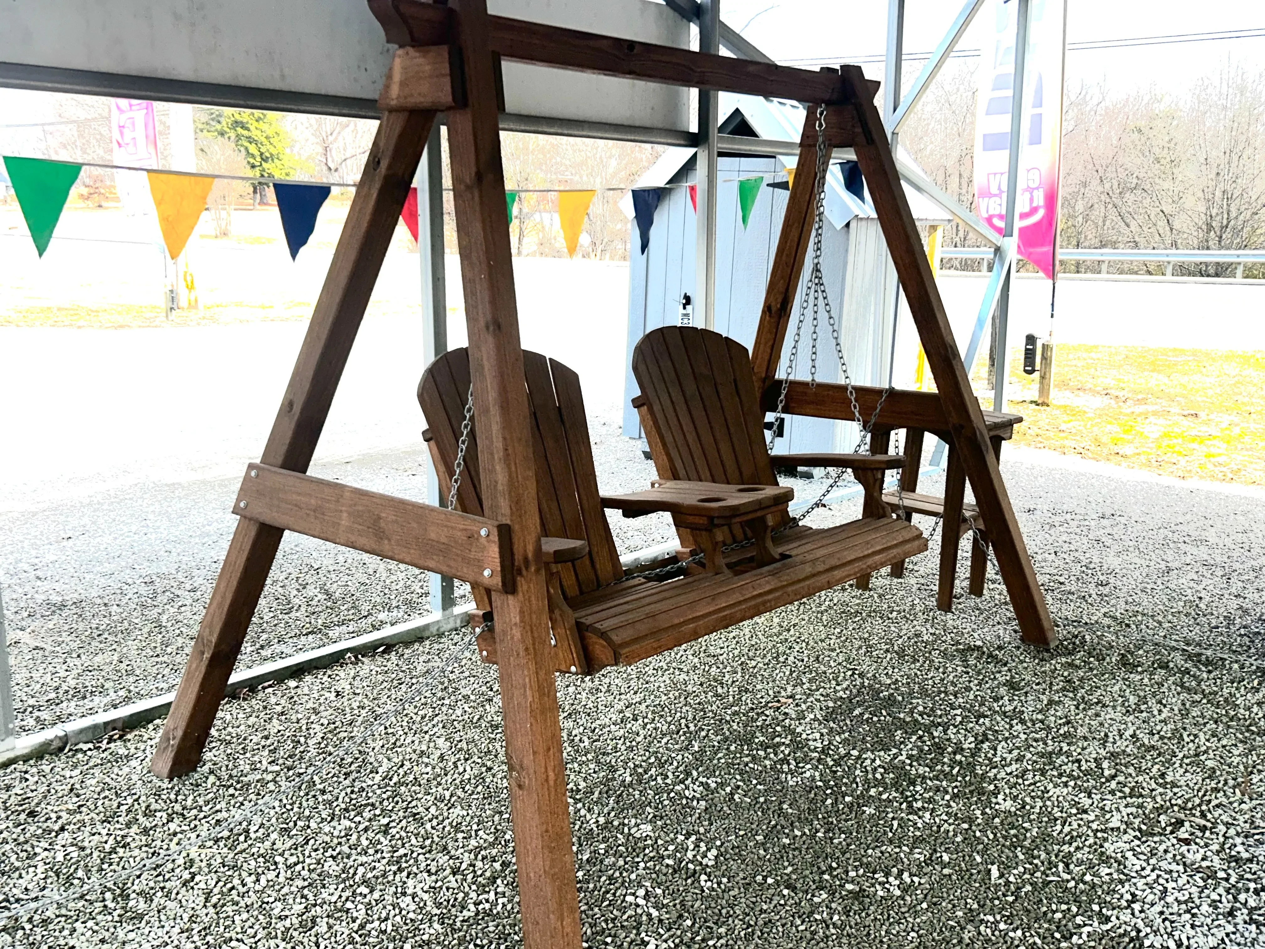 a wooden a-frame structure holding up a wood bench with a center console. It is sitting in the gravel