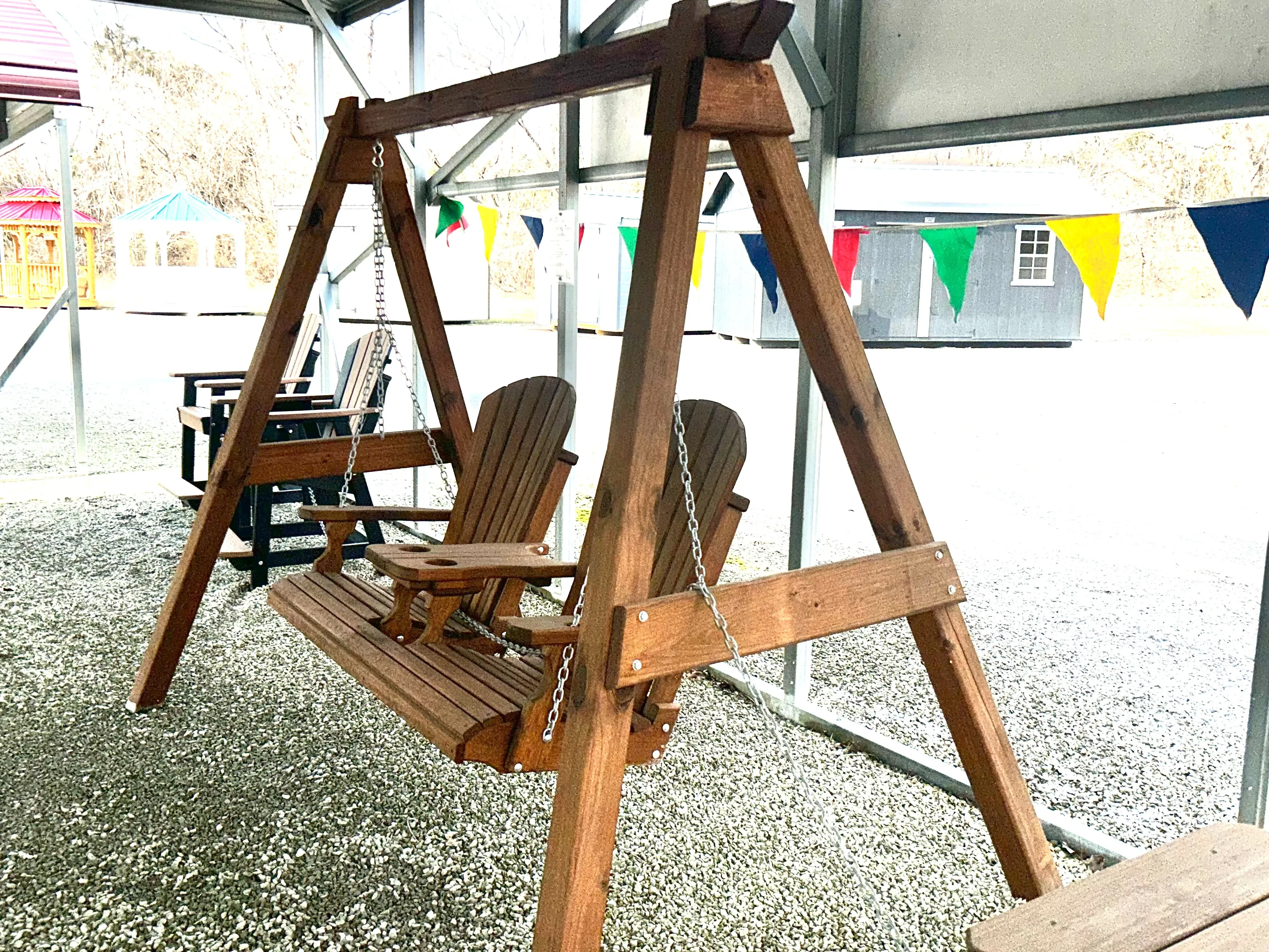 a bench attached to a wooden a-frame structure so it can swing back and forth. It is under a carport