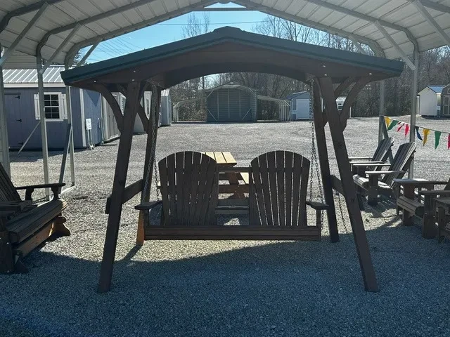 a wooded bench held up by chains to a wood swing cover with a metal roof. It is next to a bunch of other furniture