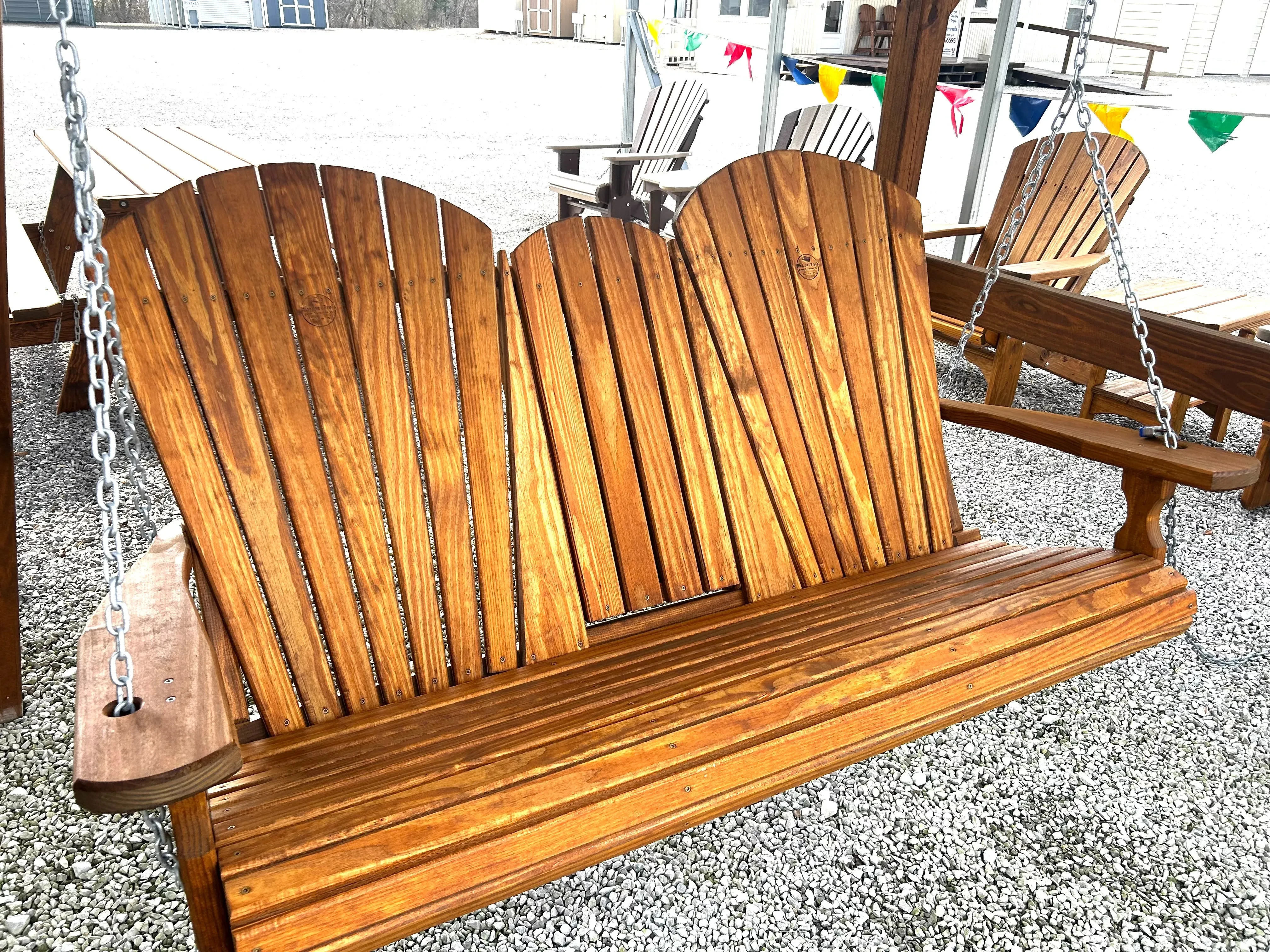 a stained and sealed wood bench swing held up by chains attached to an a-frame structure