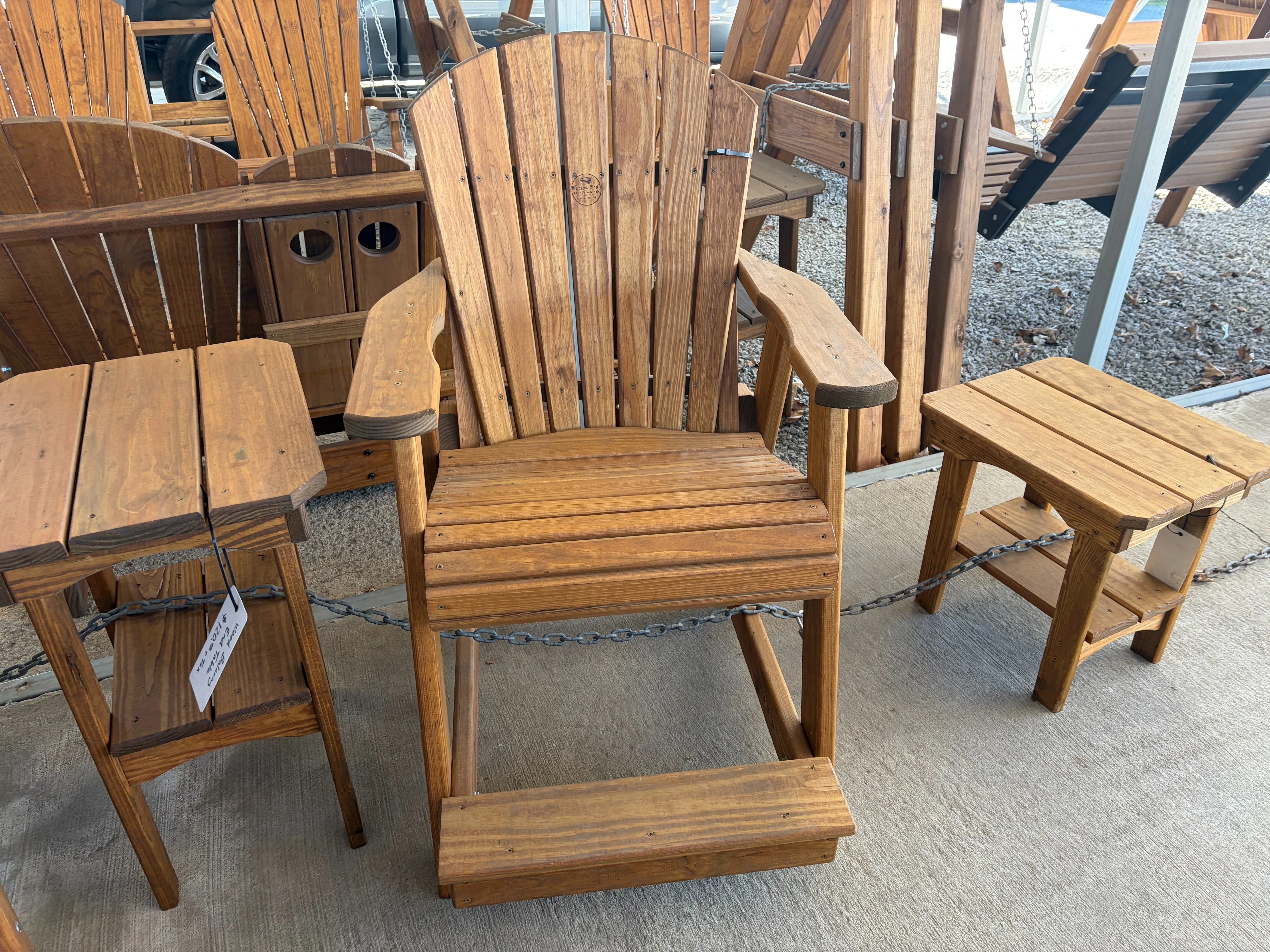 a wood chair sitting by other furniture. It is stained and sealed and it has armrests and footrests