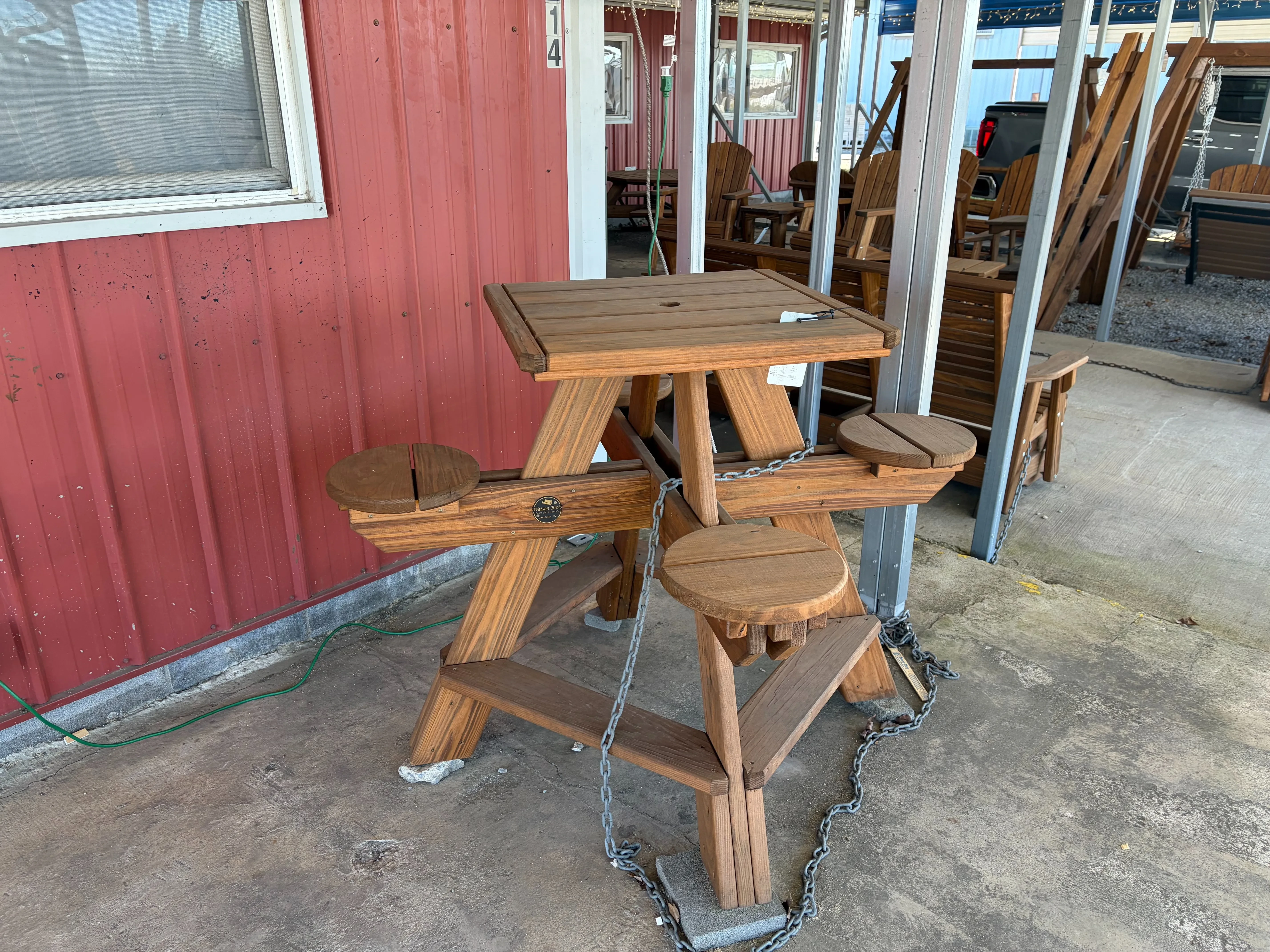 a square table with circular seats chained up to a metal pole. It is stained and sealed to last a long time