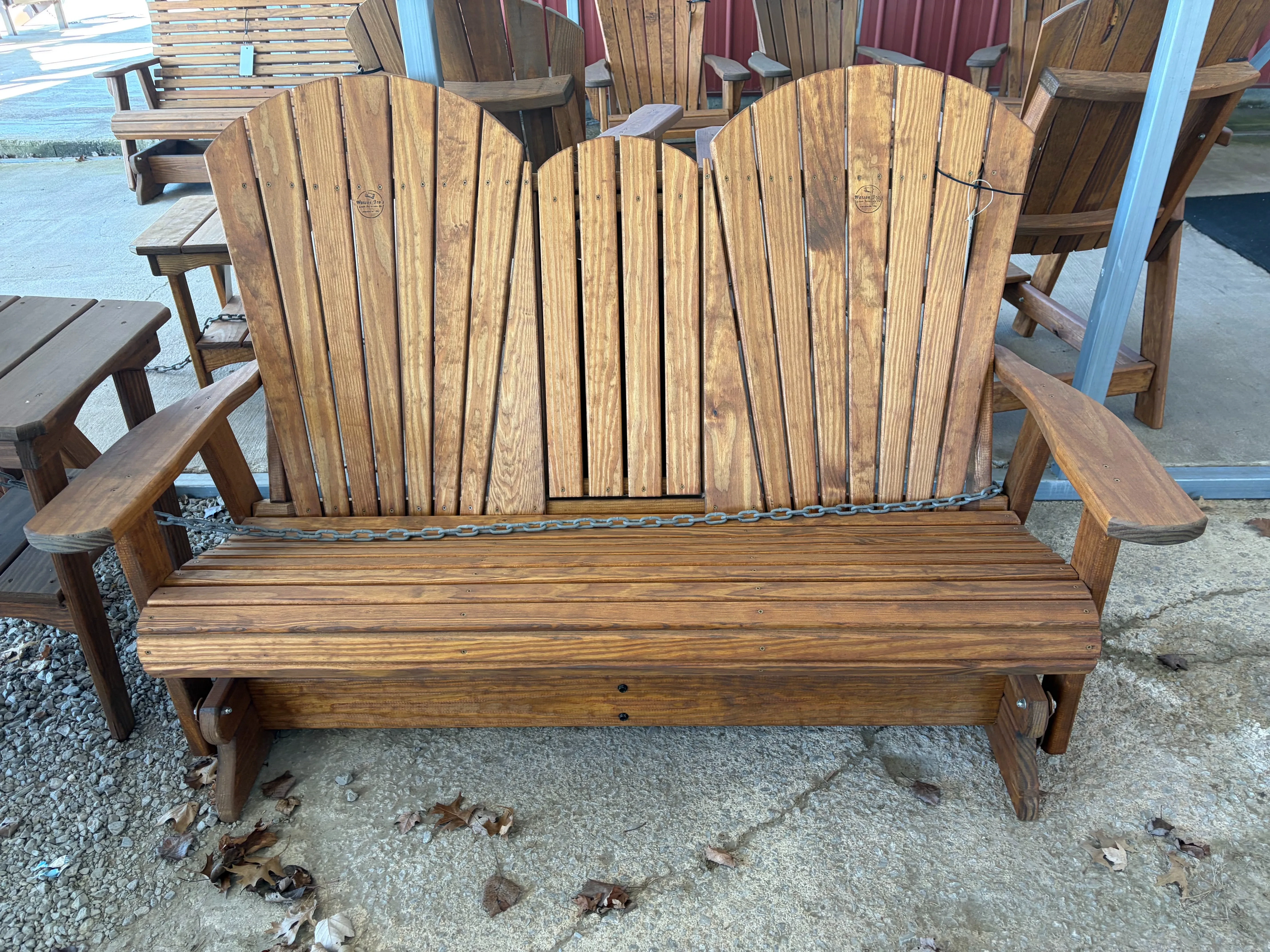 a stained and sealed wood bench that seats two. It has a center console in the up position. It is chained up