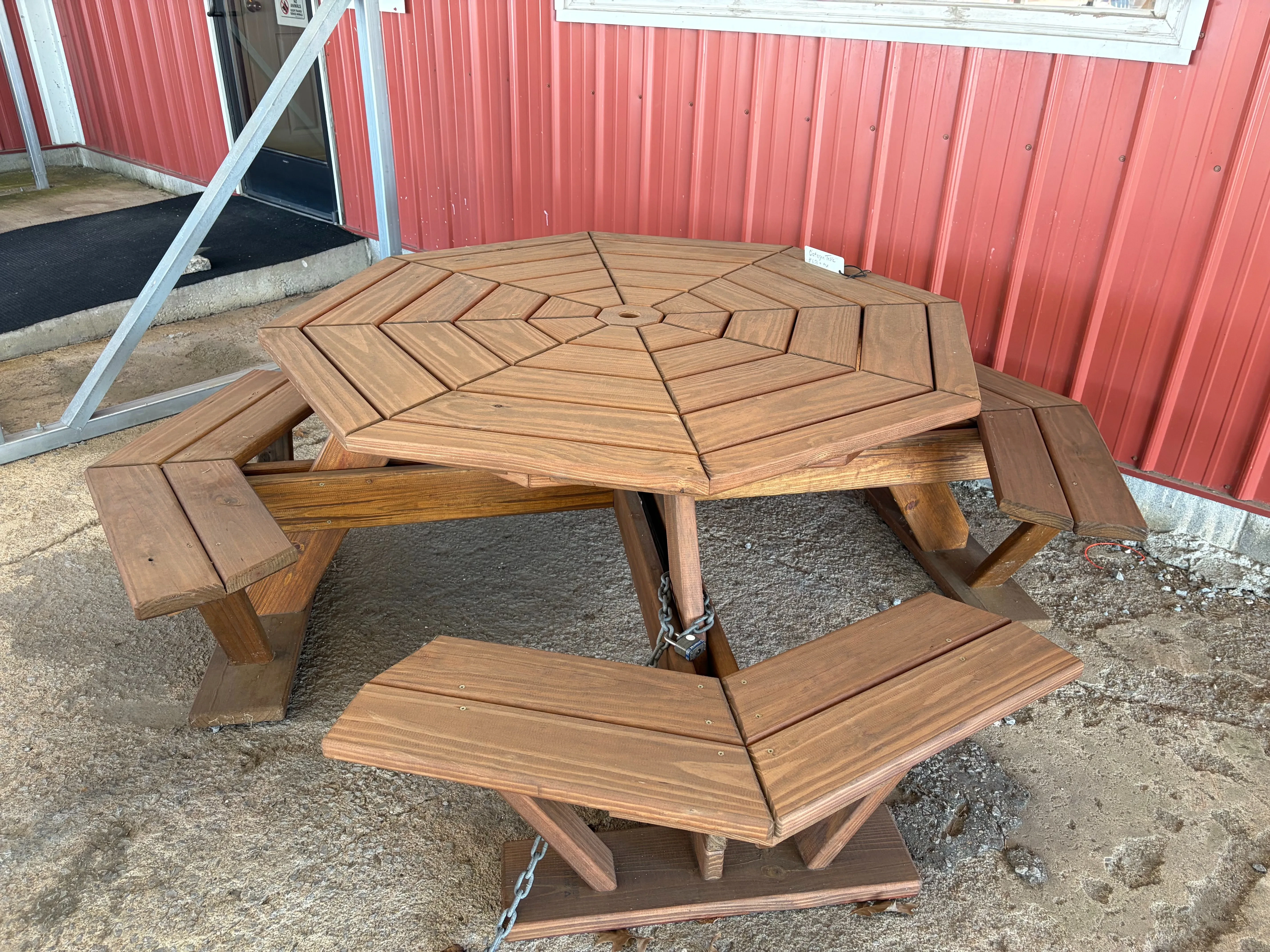 a stained and sealed wood table sitting on concrete. It is cut and built in a way which it resembles an octagon