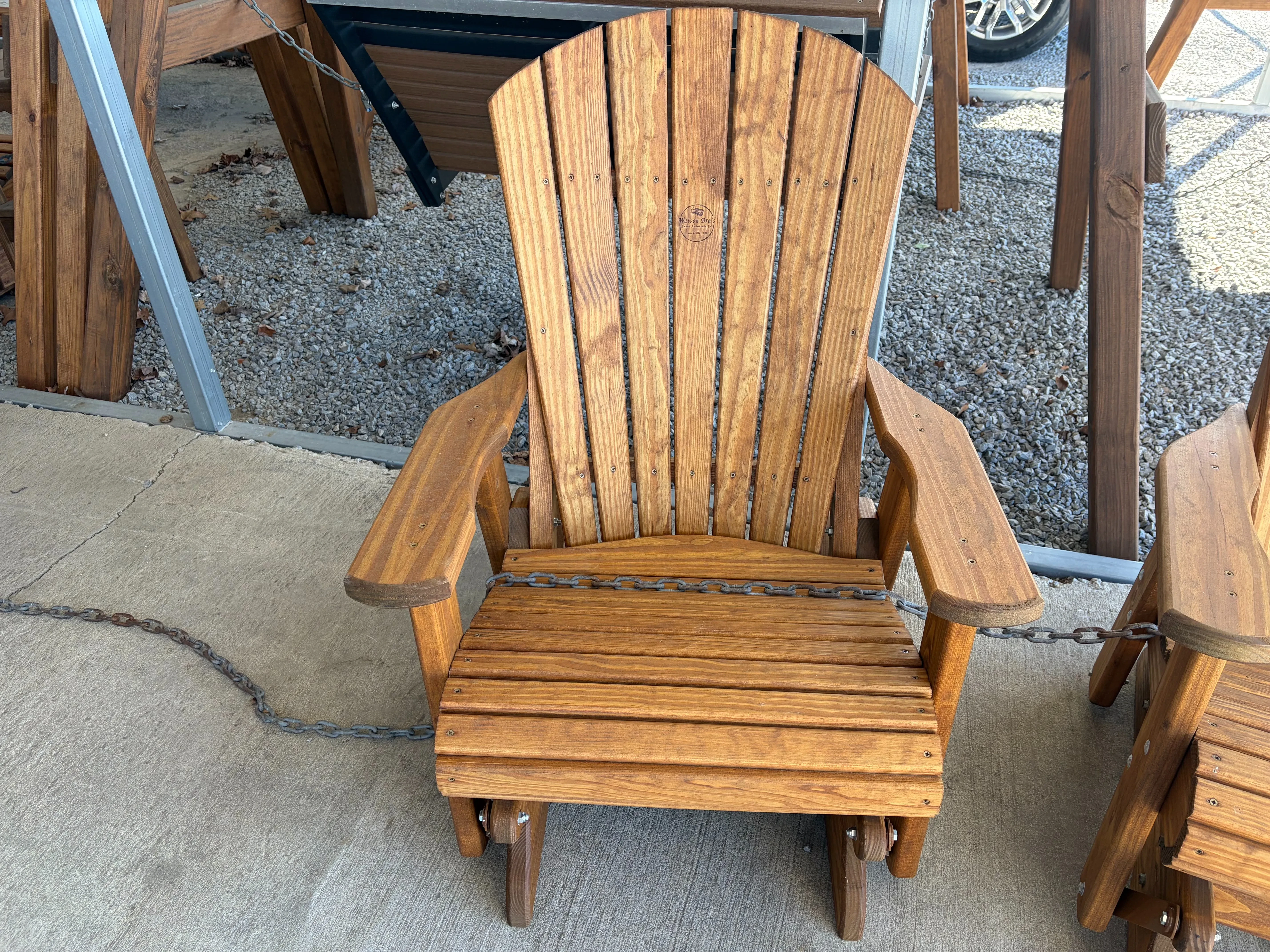a stained and sealed wood chair that can glide back and forth. It is chained up and sitting on concrete.