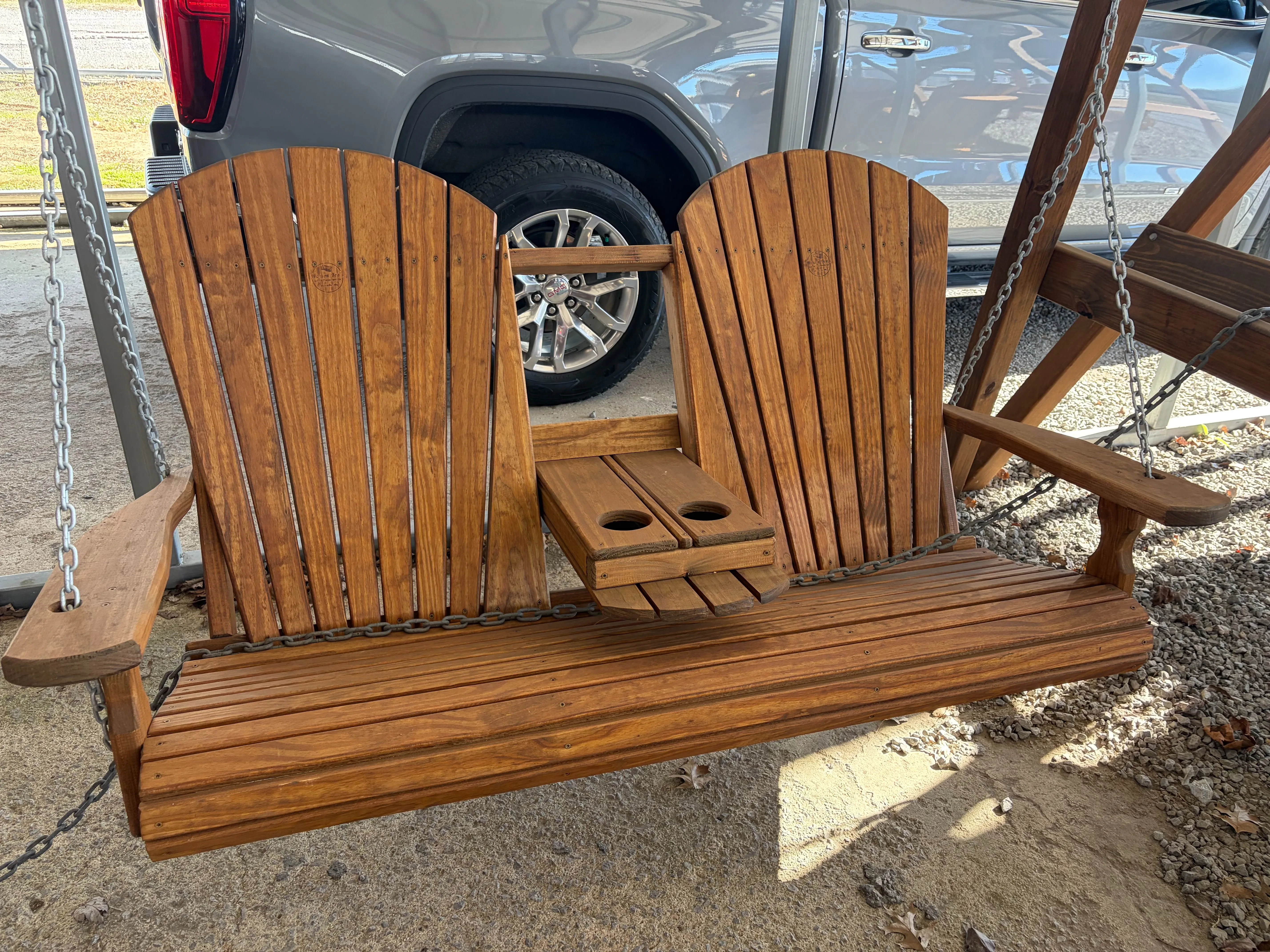 a wood bench swing that seats two. It has a center console with two cupholders in the down position.