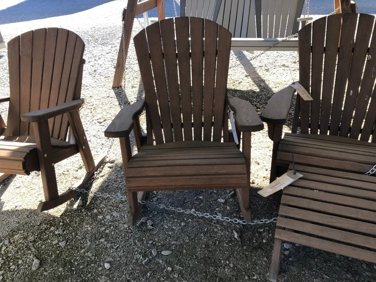 a rocking chair sitting in the shade. It is stained and sealed professionally. It is chained up to other chairs nearby