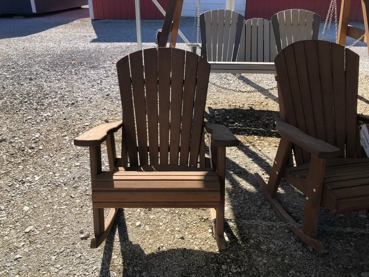 a wood rocking chair sitting in the shade. It is stained and sealed nicely. It is chained up to another chair next to it