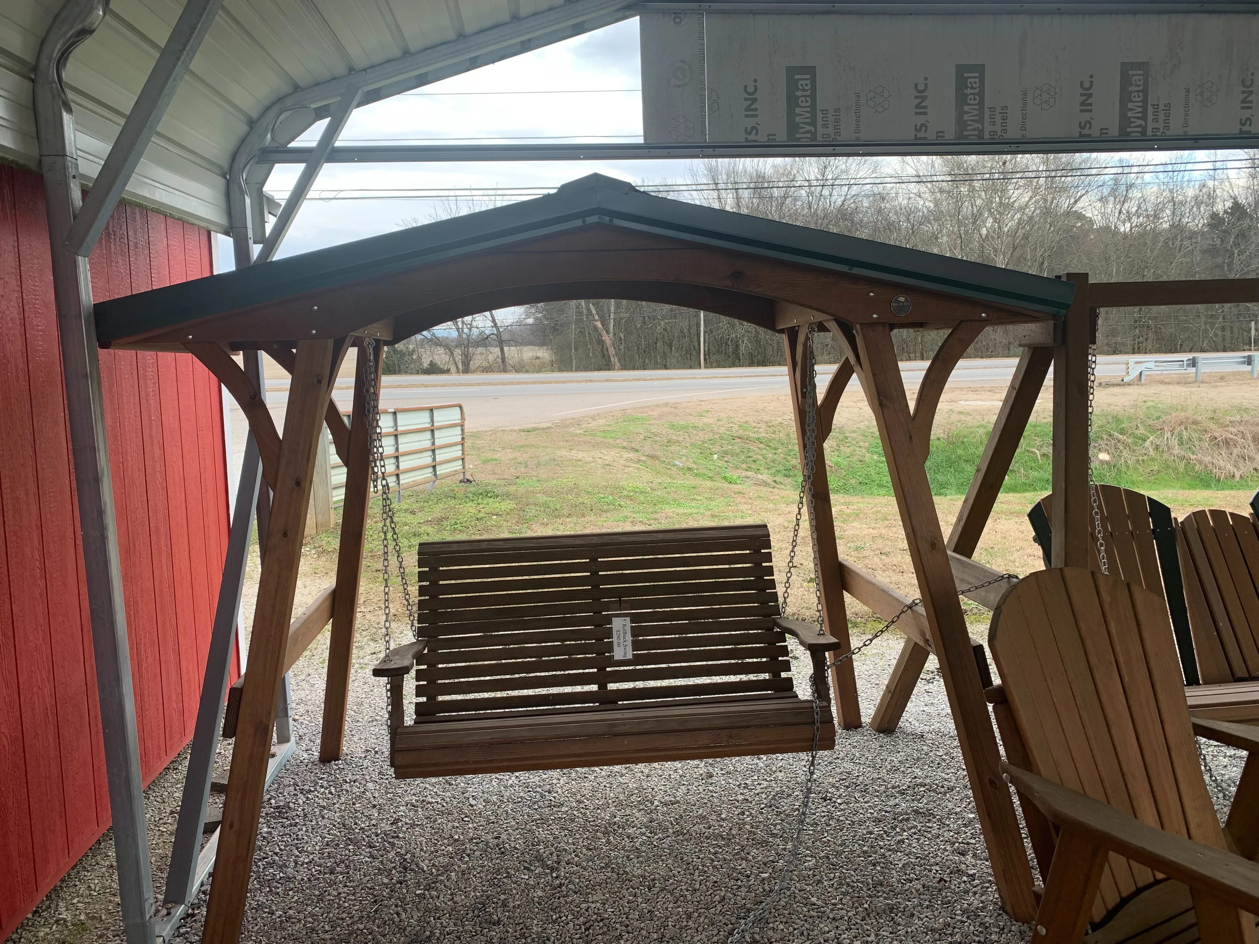 a wooden swing cover that is holding up a wood bench by chains. The swing cover is made of wood and has a metal roof