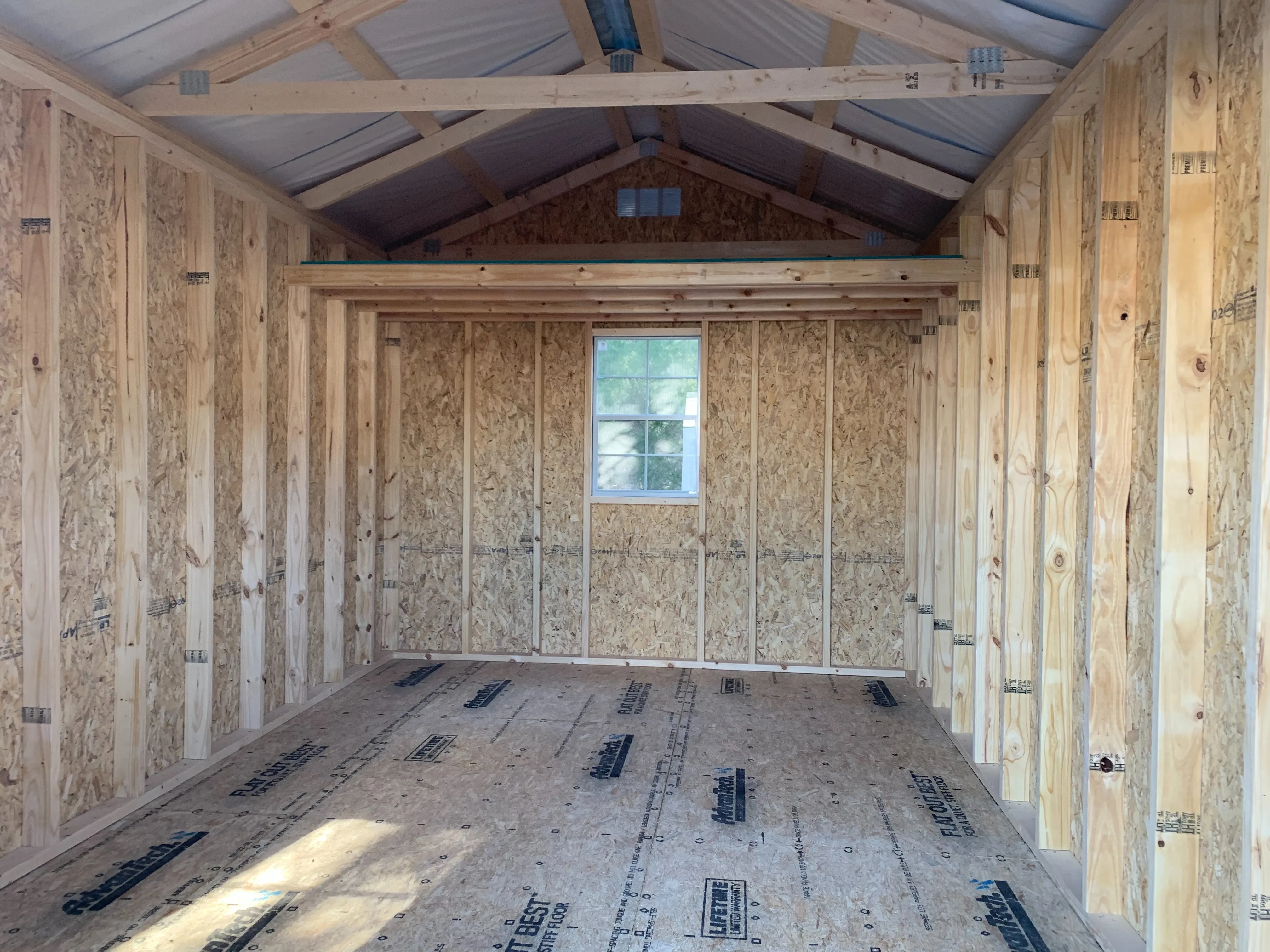 inside a wood shed with a window in the middle of the back wall and loft