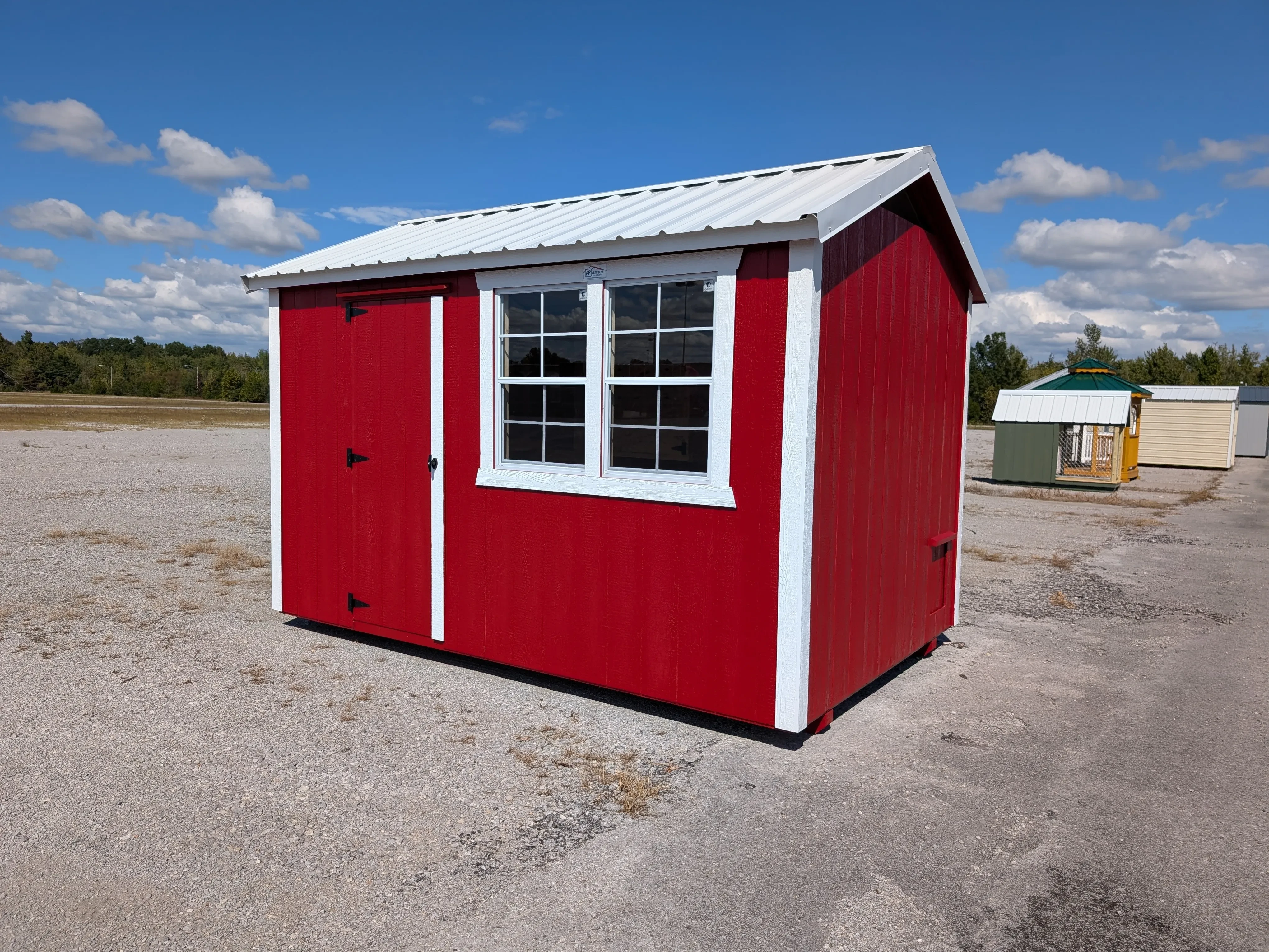 a red chicken coop with a 30" walk-in door. It has two windows and white trim. It has a white metal roof