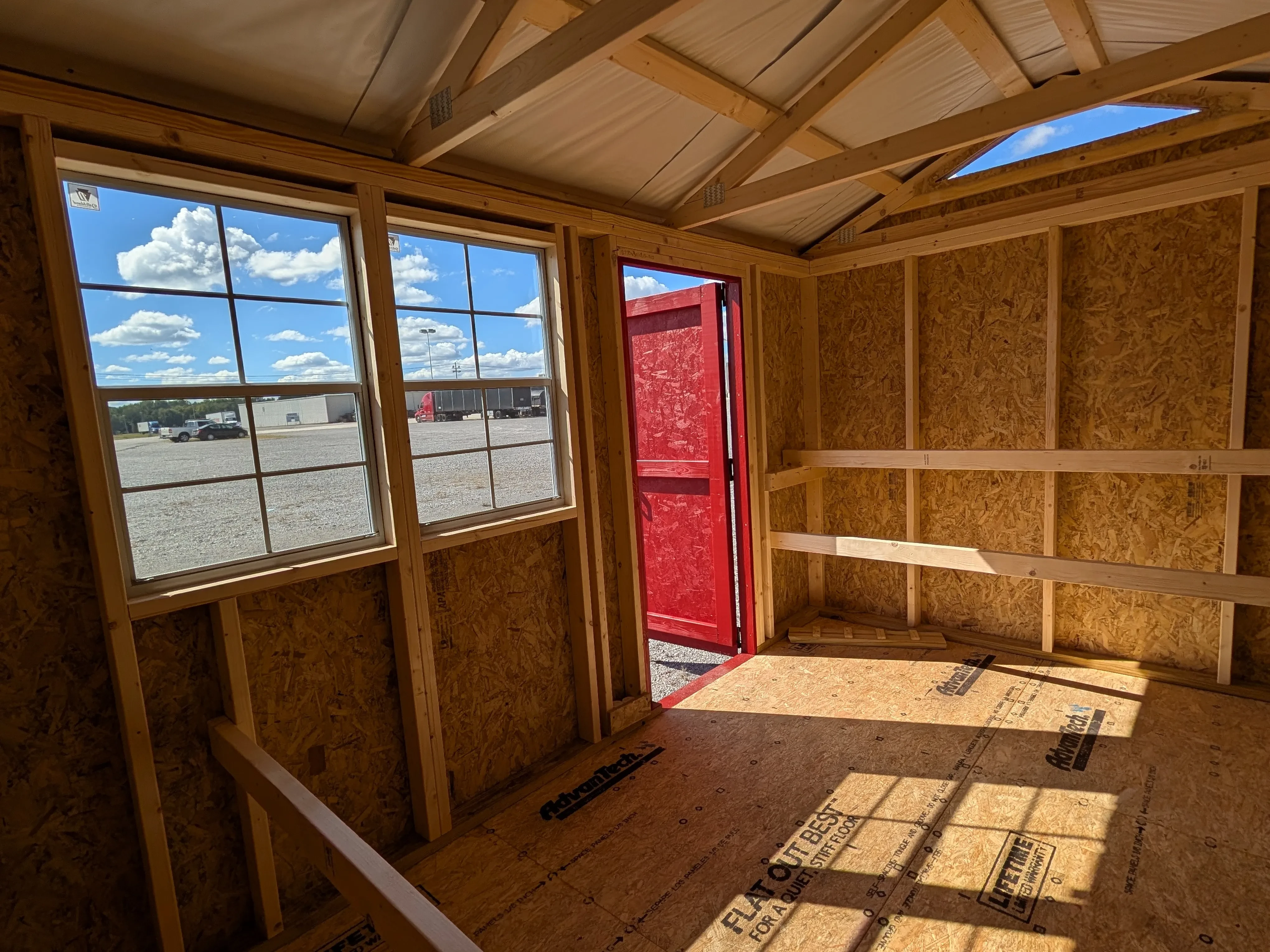 inside a wood chicken coop. The walk-in door is open and you can see three roosting bars for chickens to perch on