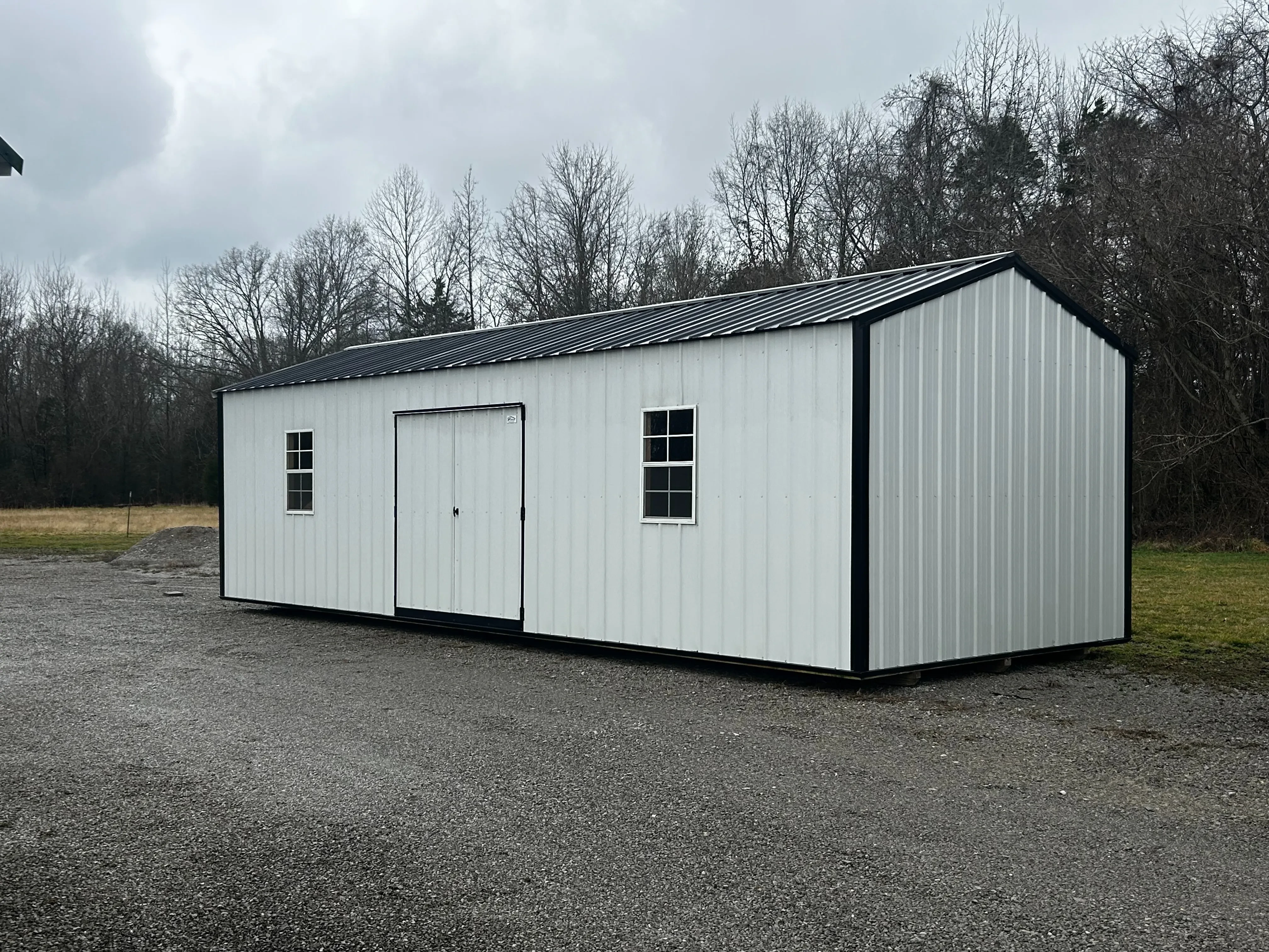 Front left side of a 12x32 utility garage showing its 80" double doors and 2x3 windows.