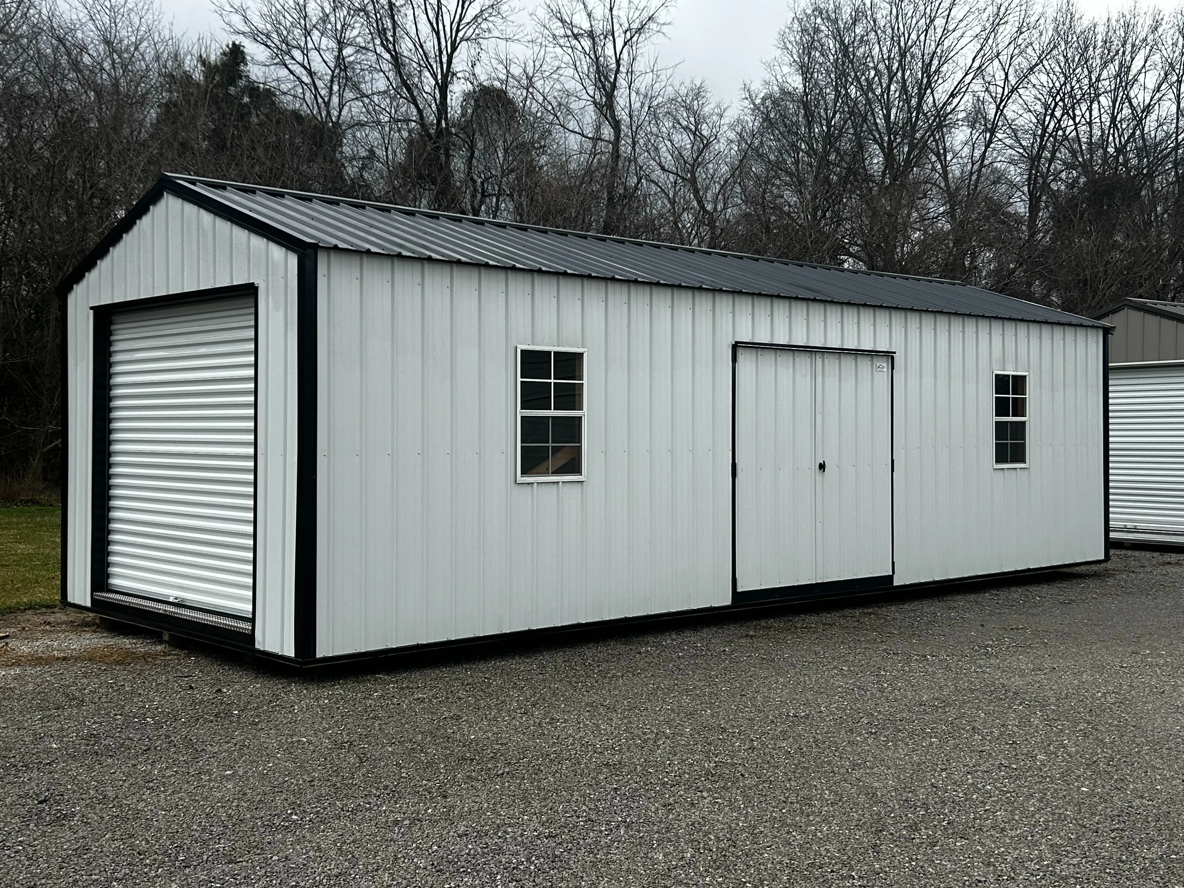 A 12x32 utility garage from its front left showing an 8x7 roll-up door, double doors and windows.