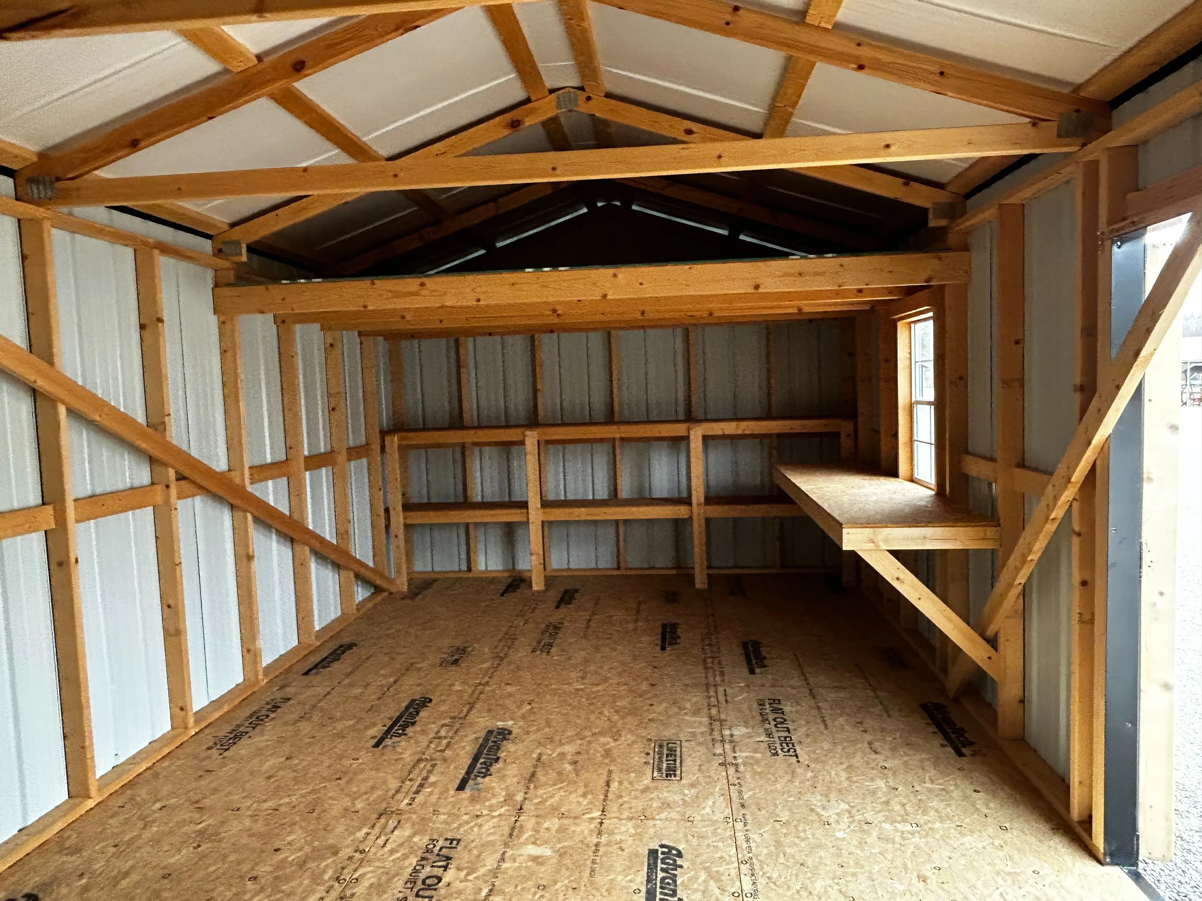 The inside right view of a 12x32 garage showing loft, shelving and workbench.