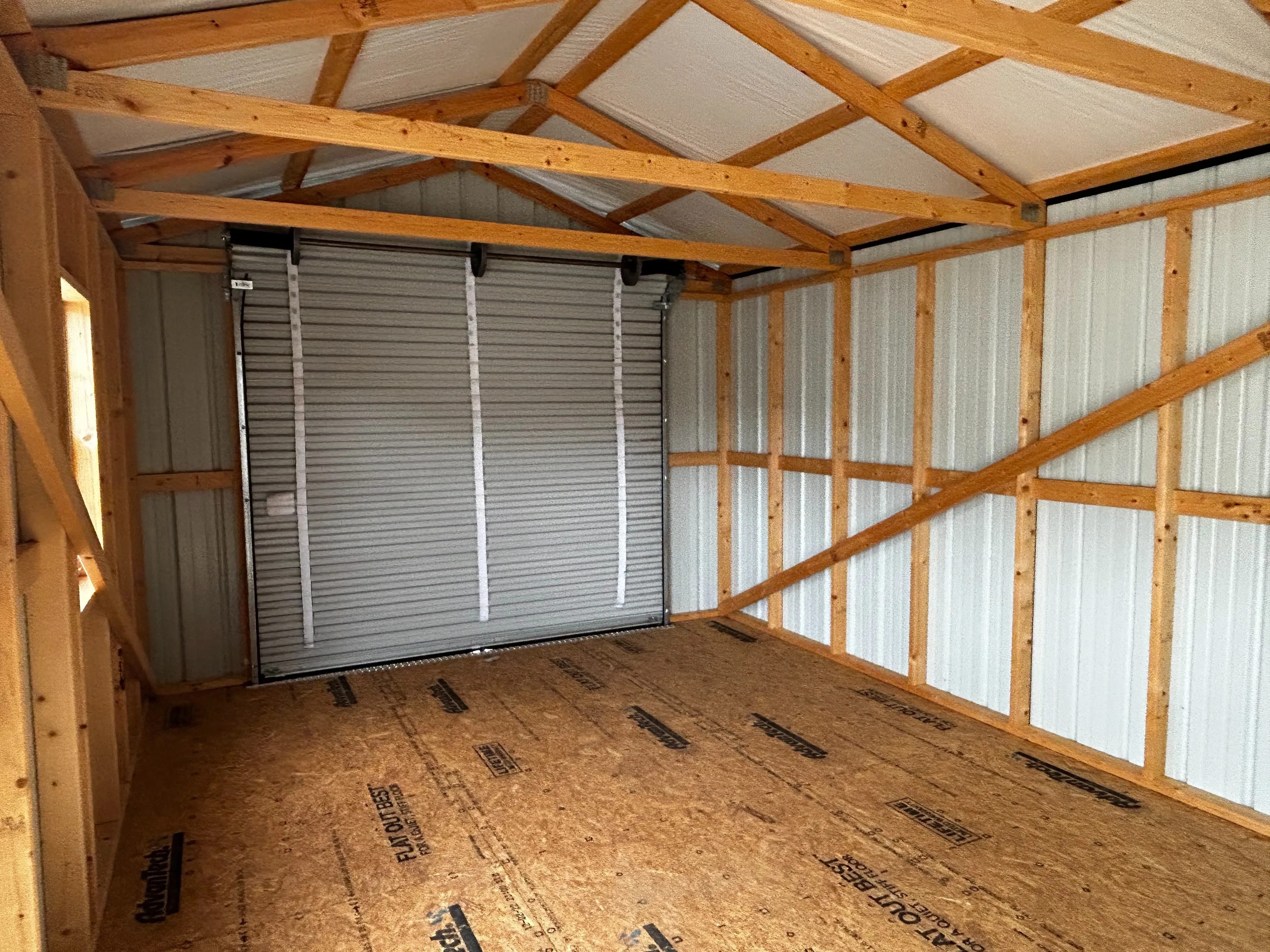The inside left view of 12x32 garage showing large space, roll-up door and its hardware.